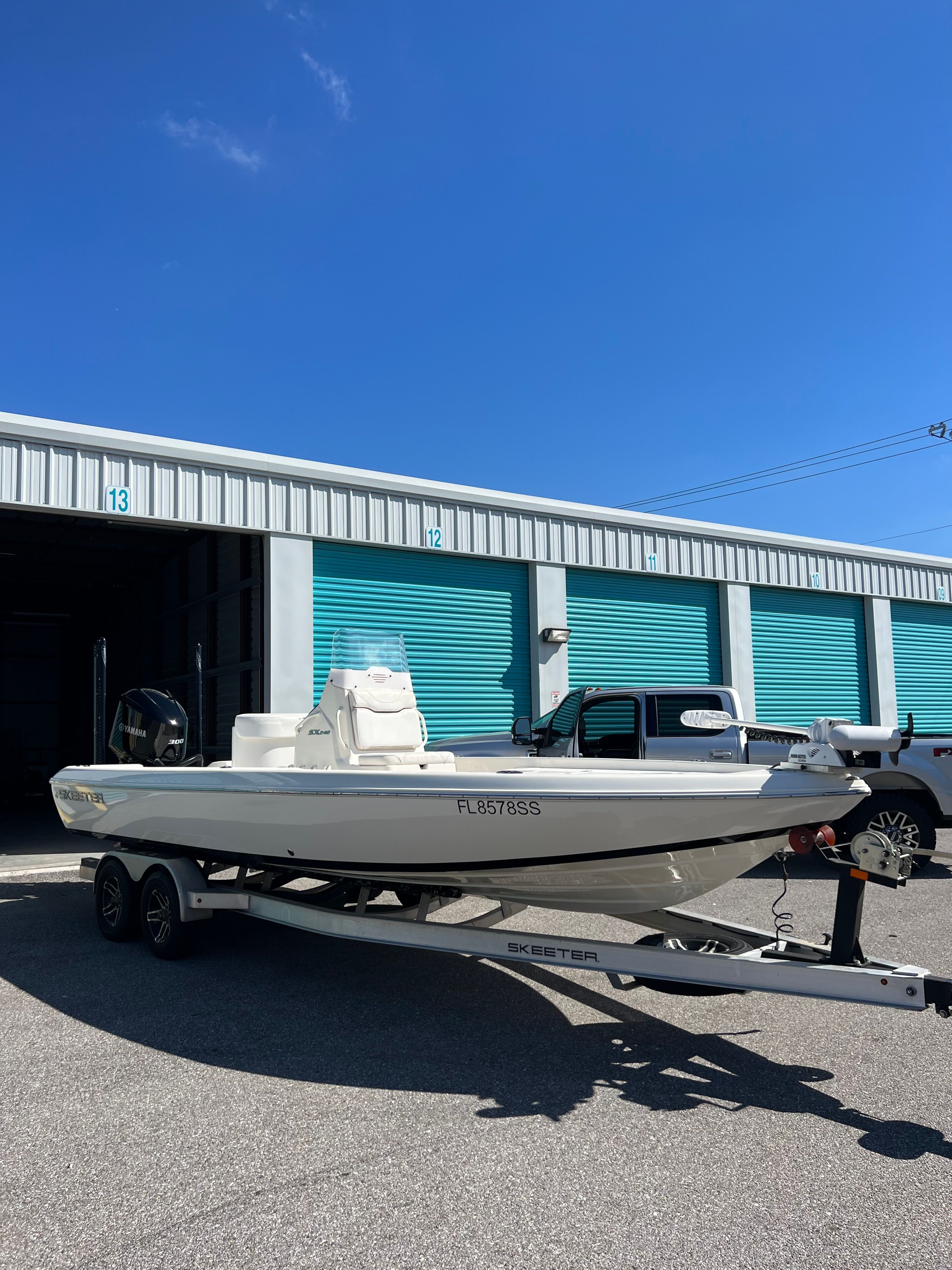 A white 2020 Skeeter SX240 boat on a trailer in front of storage units.