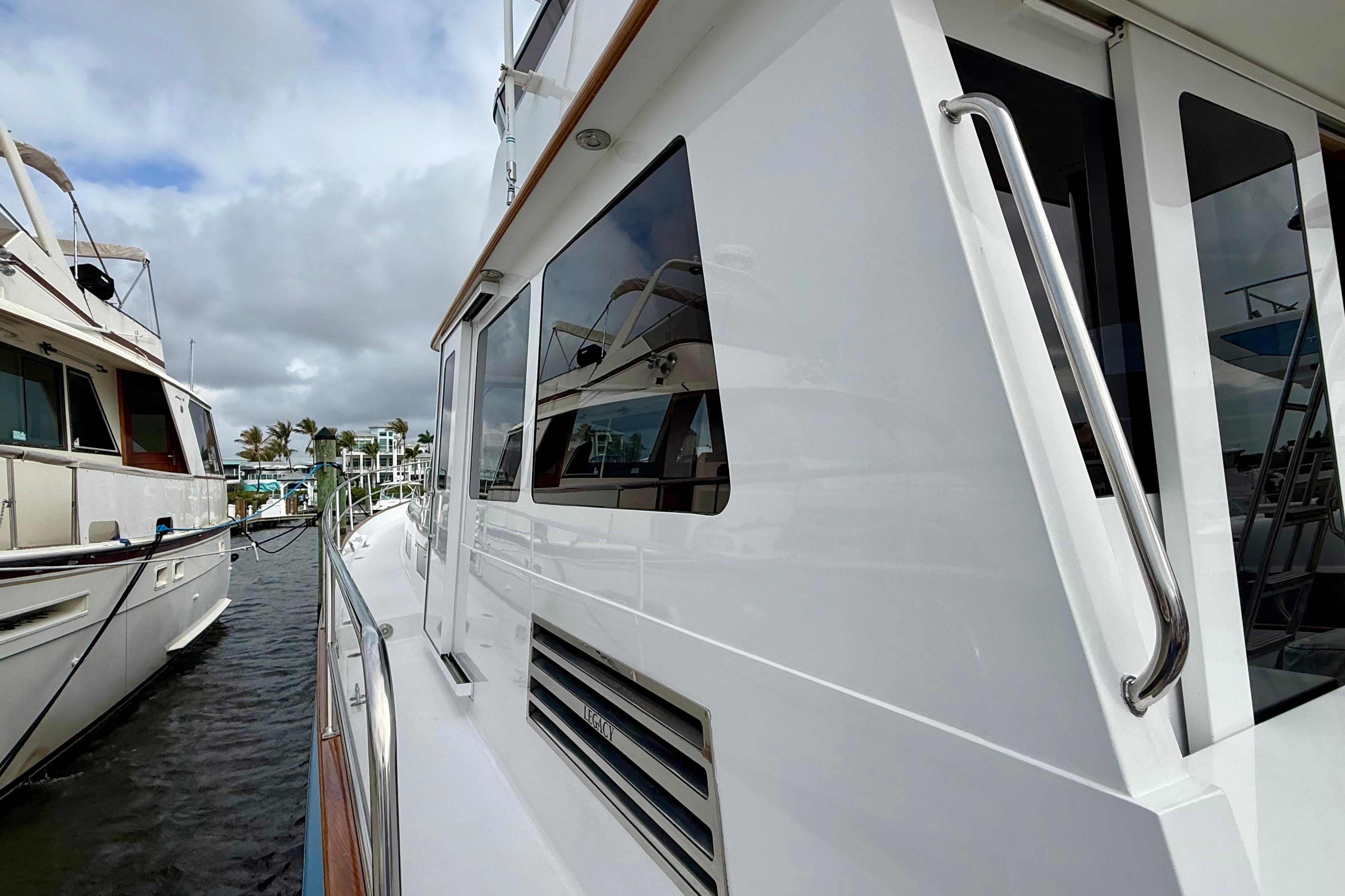 2002 Legacy 52 yacht docked, showcasing sleek white exterior and reflective windows.