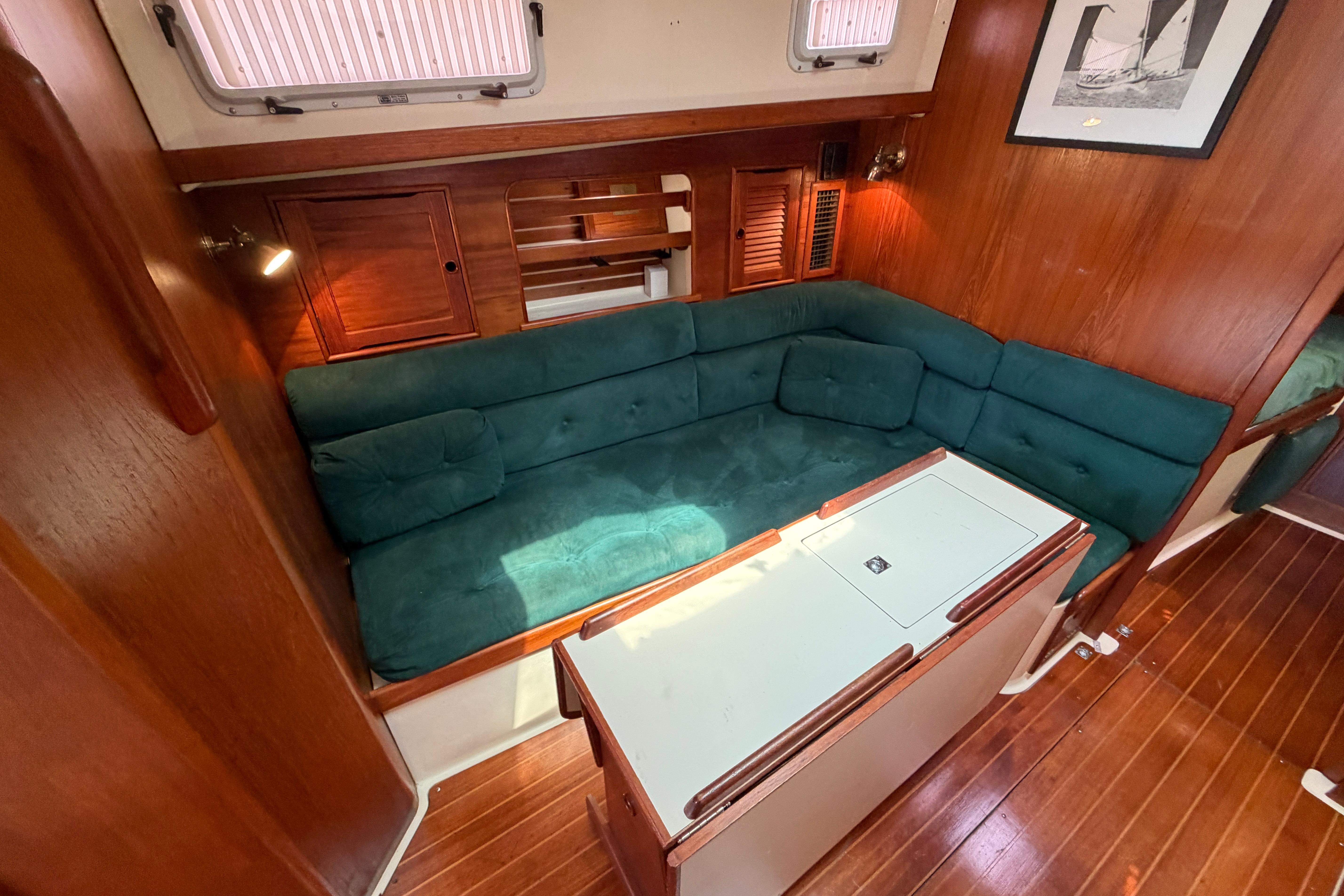 Interior of 1989 Nonsuch 36 sailboat with green cushioned seating and wooden accents.