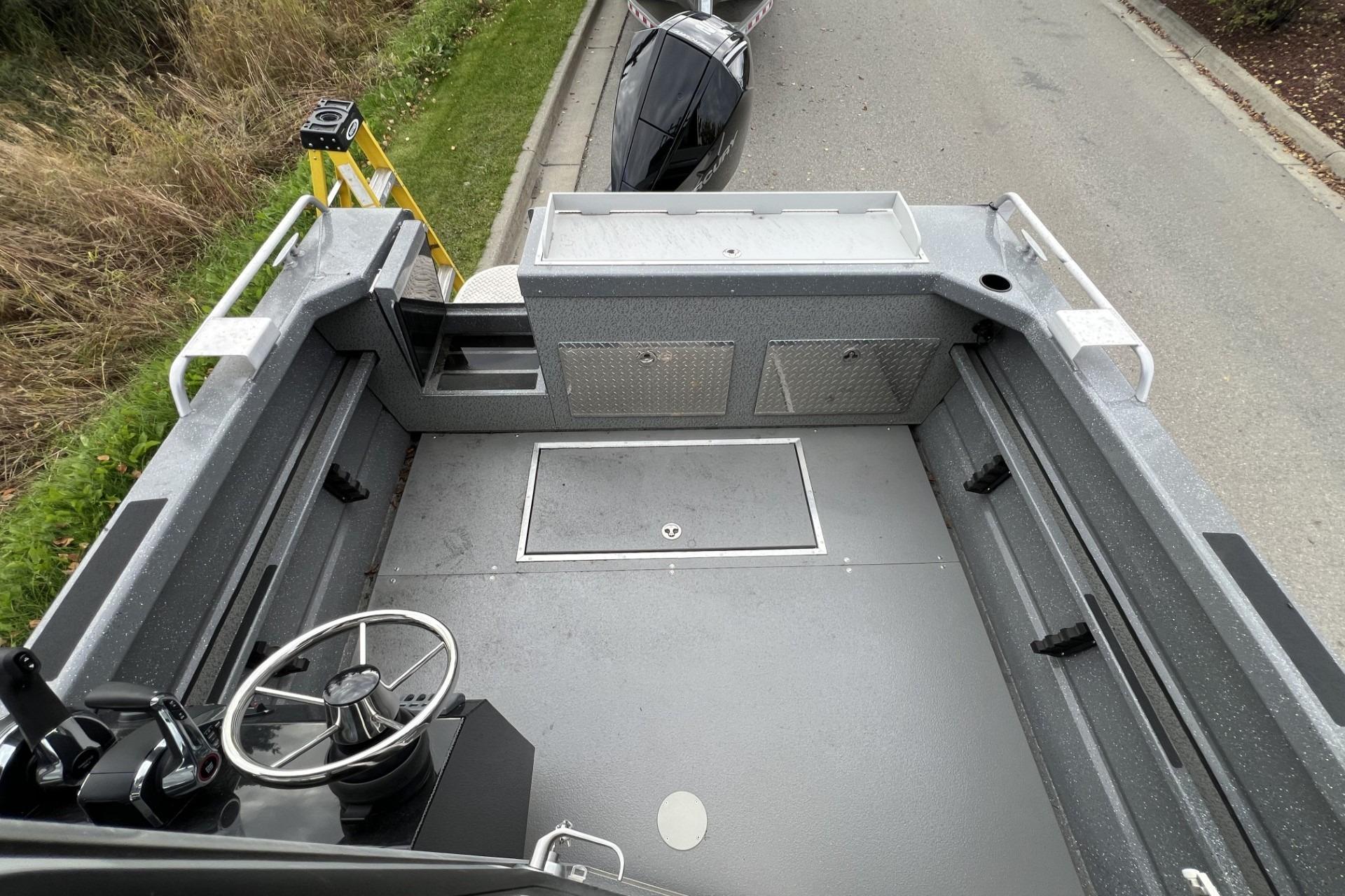 2024 Spartan 220 Maximus boat interior with steering wheel and storage compartments.