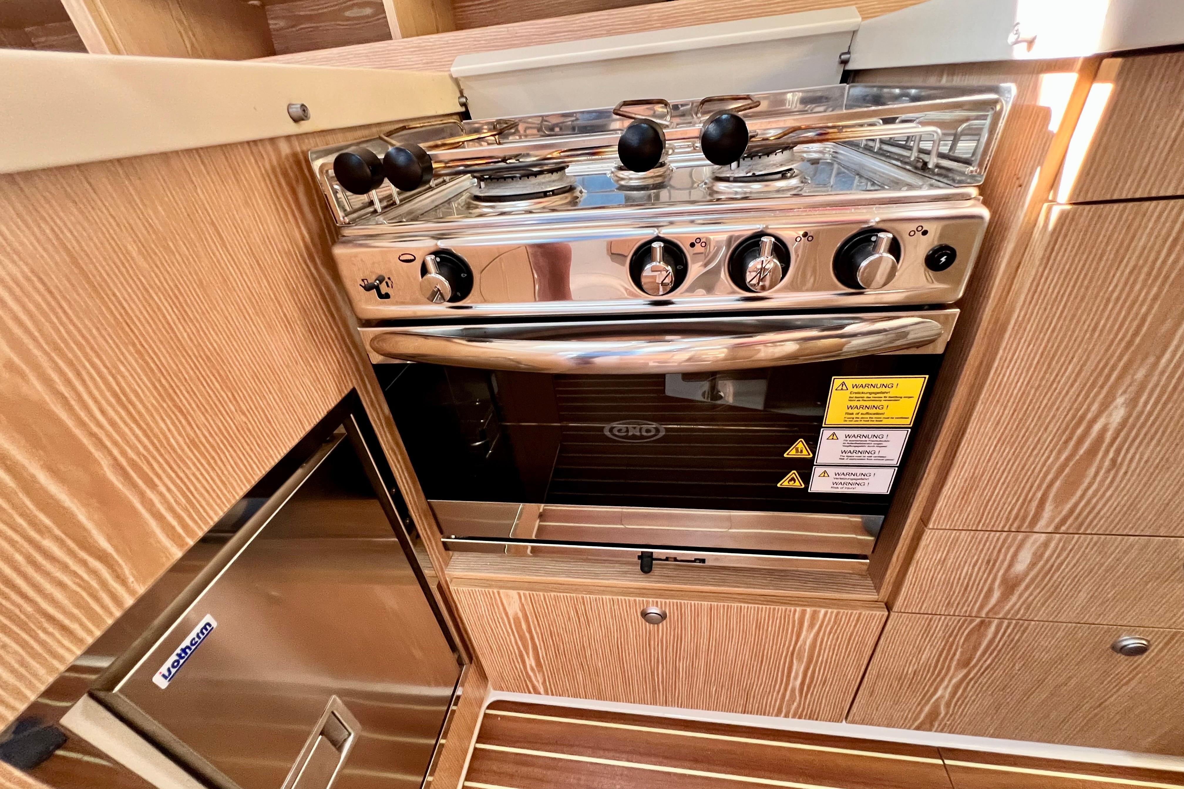 Modern kitchen in 2016 Hanse 455 yacht with stainless steel stove and wooden cabinetry.