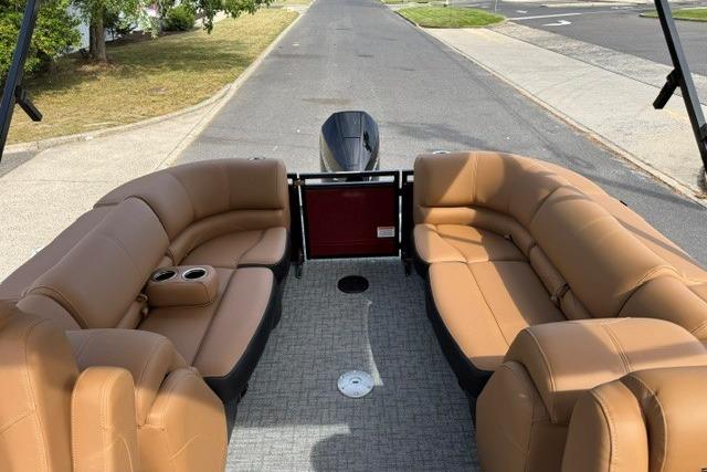 Luxurious interior of 2026 Regency 230 DL pontoon boat with tan seating and cup holders.
