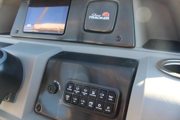 Dashboard of 2025 Sun Tracker Fishin' Barge 22 DLX with control panel and logo.