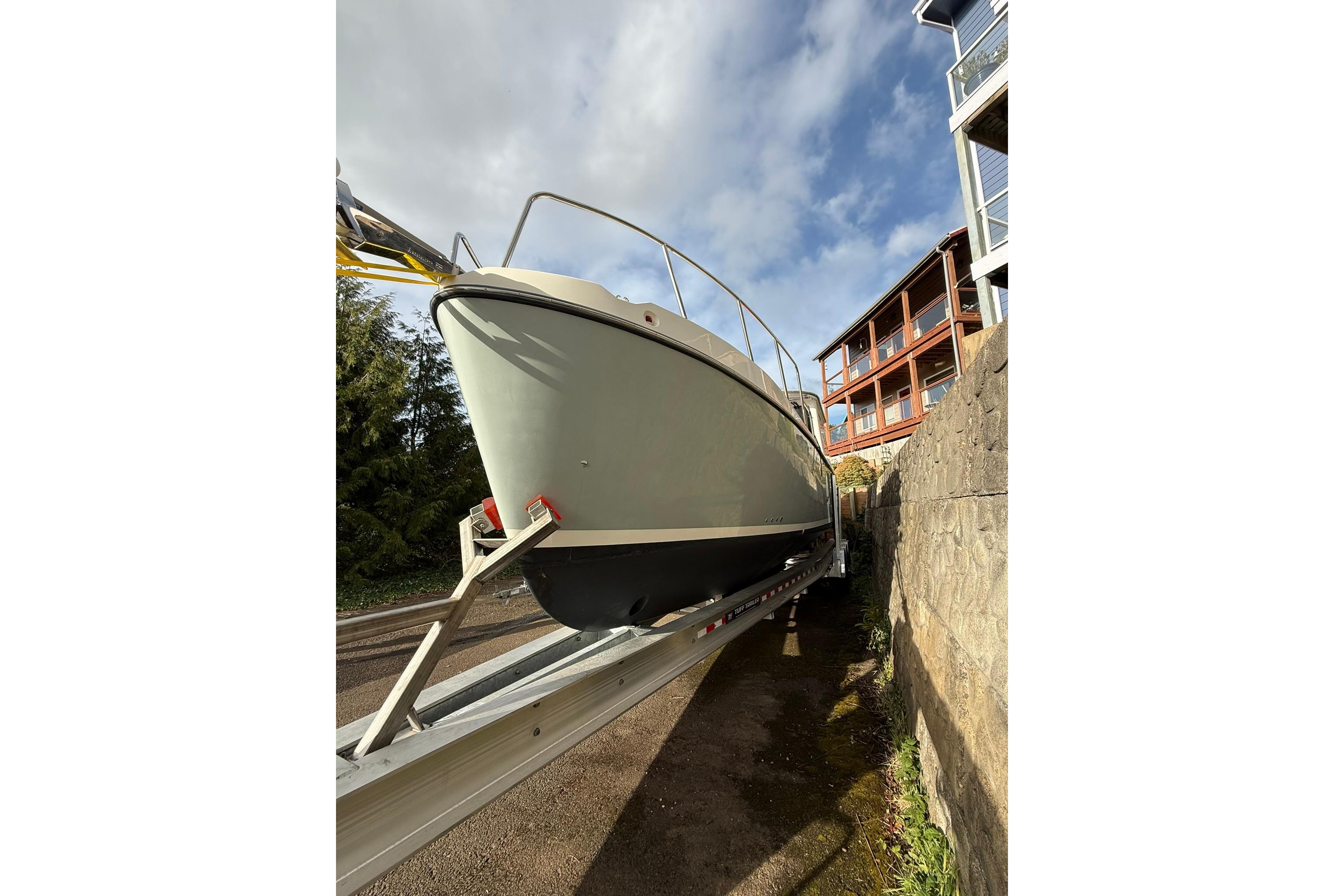 2020 SeaPiper 35 boat on trailer, parked beside a building under a cloudy sky.