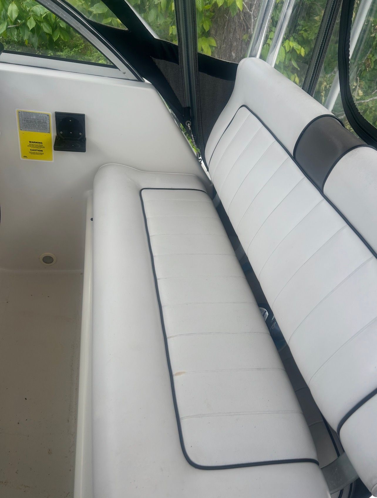 Interior view of a boat with white cushioned seating and a control area.