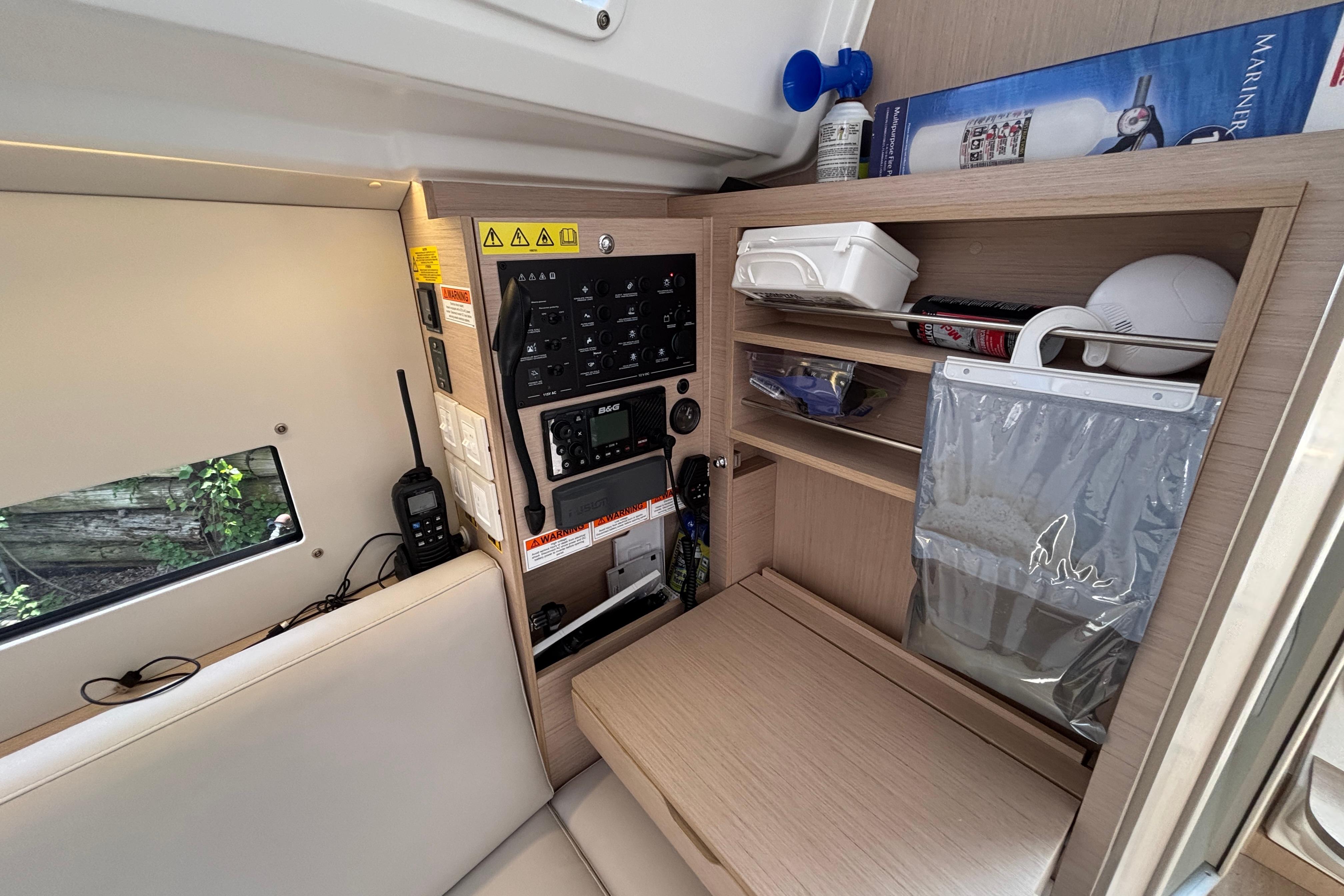 Interior of a 2021 Beneteau Oceanis 30.1 yacht with navigation equipment and storage shelves.