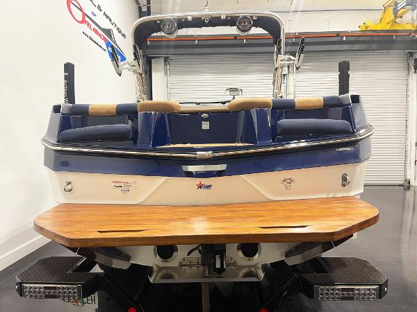 2022 MasterCraft NXT24 boat, blue and white, rear view with wooden swim platform.