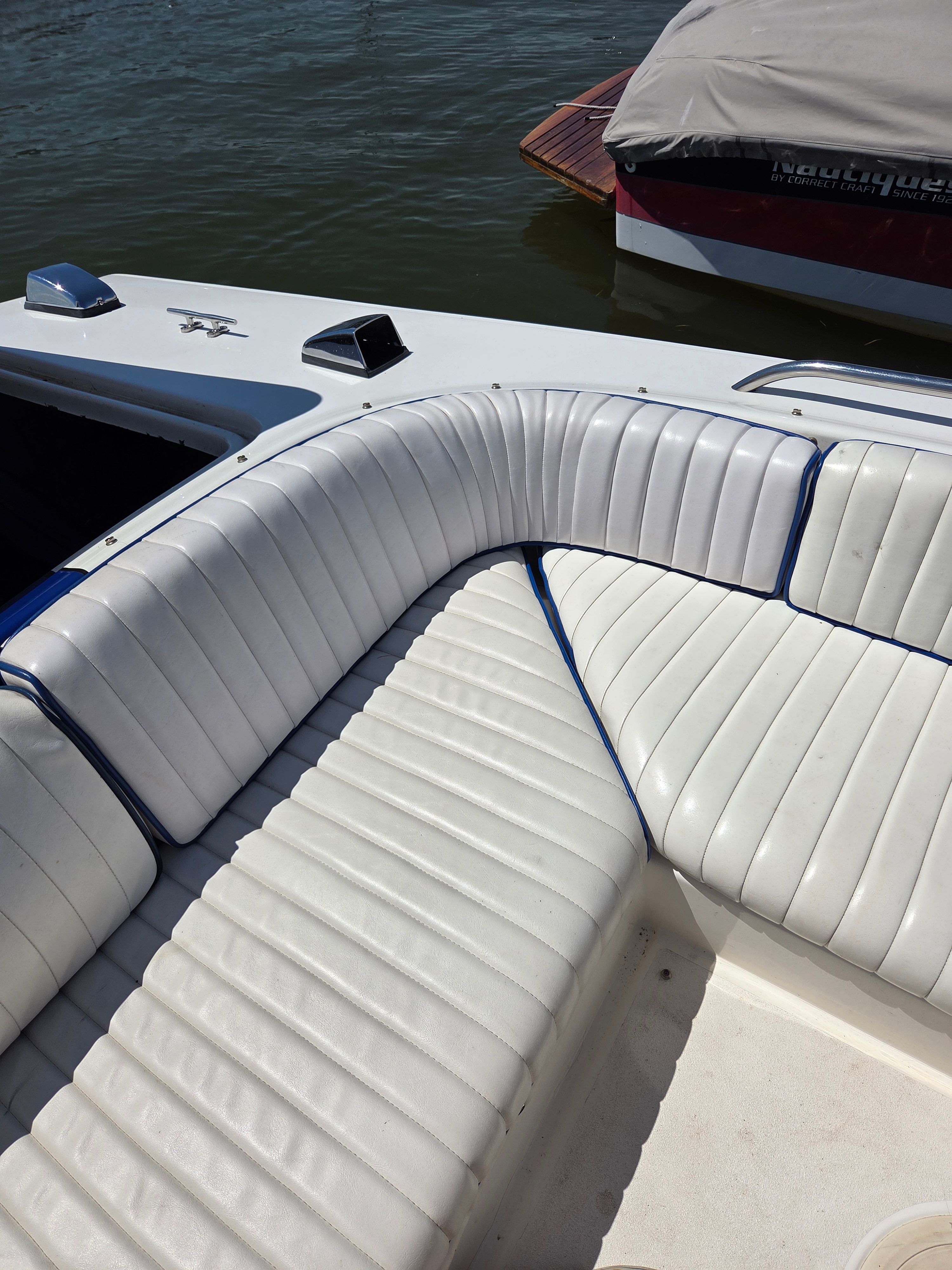 White cushioned seating in a boat with blue accents, on calm water.