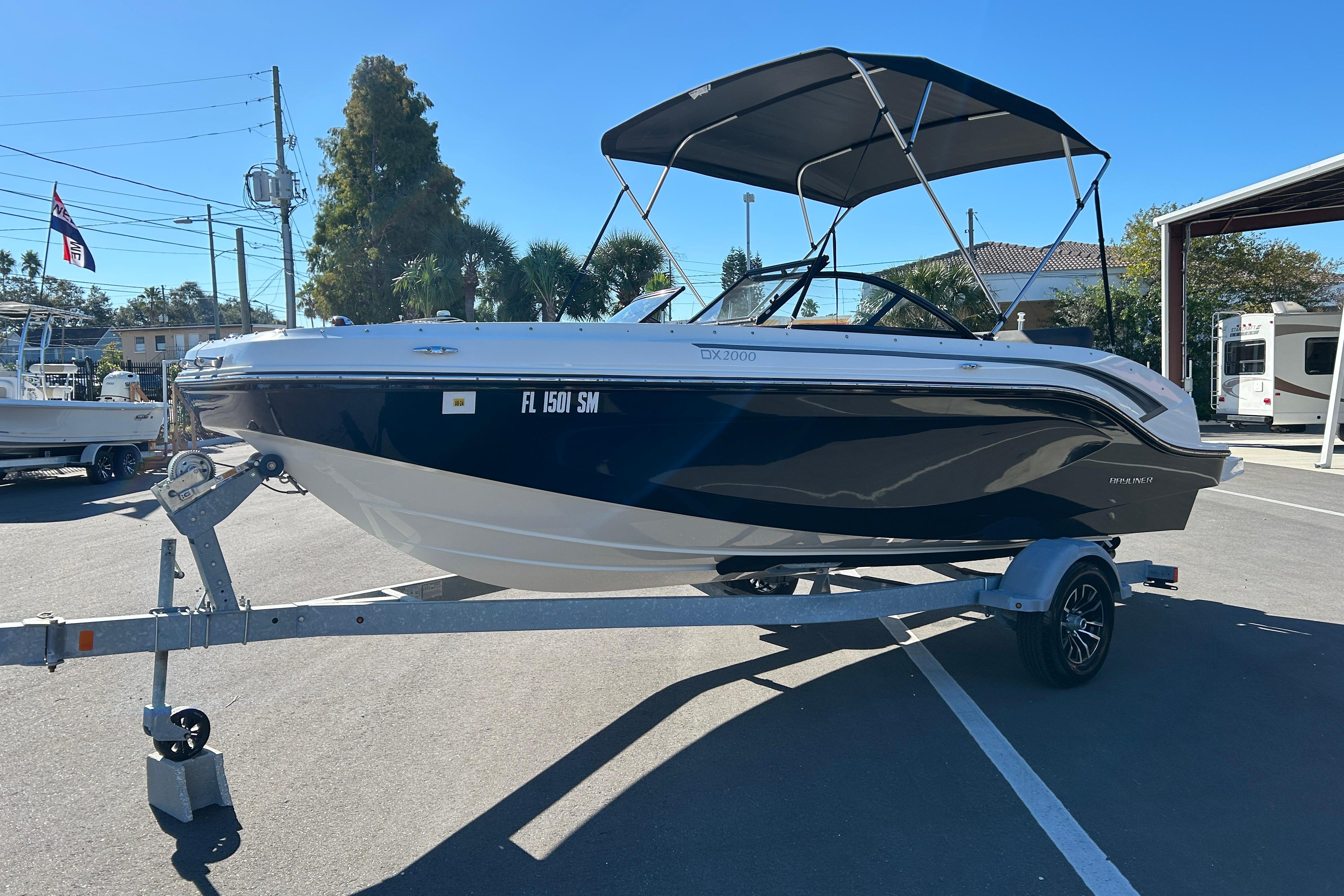 2020 Bayliner DX 2000 boat on trailer, parked outdoors under clear blue sky.