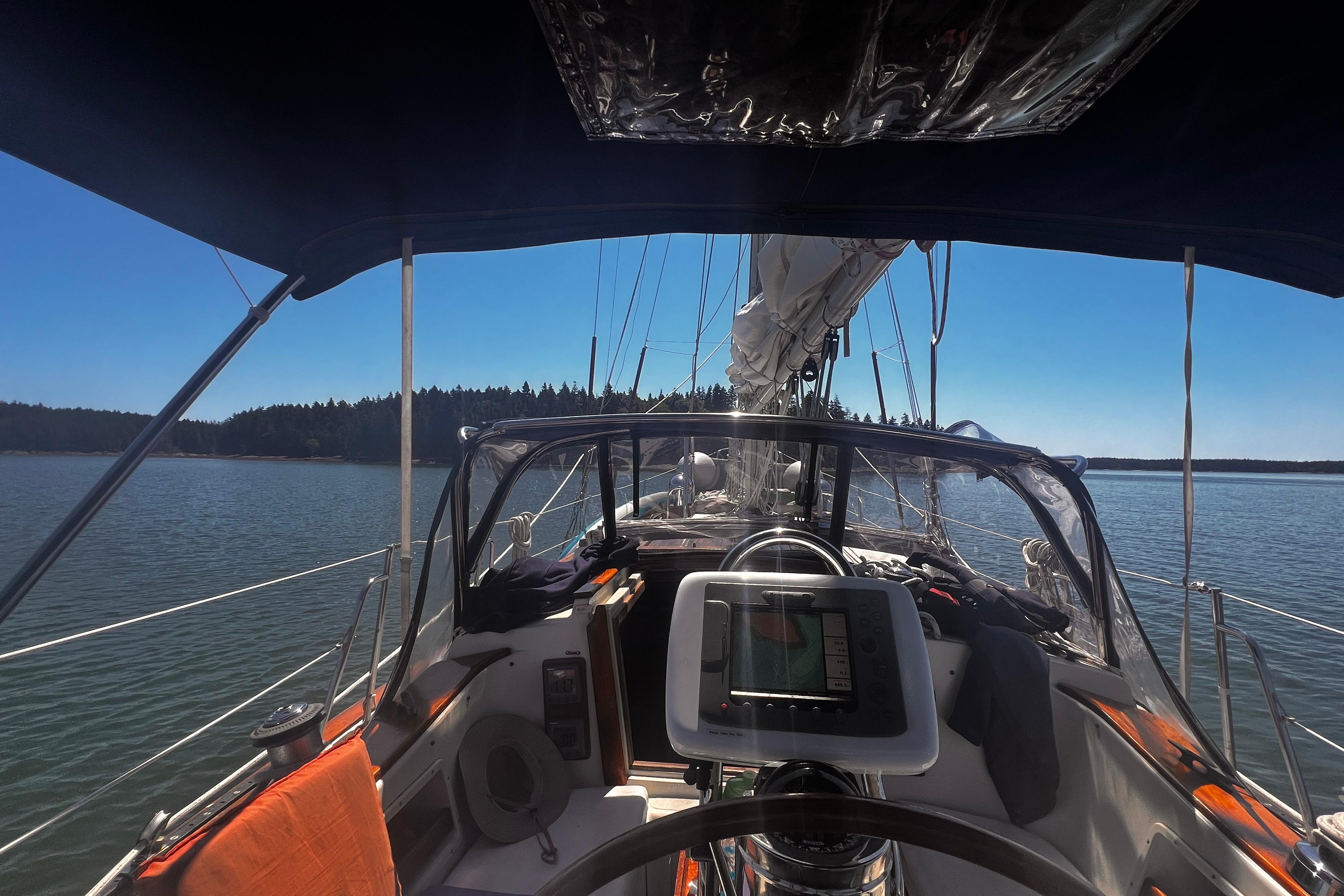 Cockpit view of 1982 Pacific Seacraft 37 sailboat on calm waters under clear blue sky.