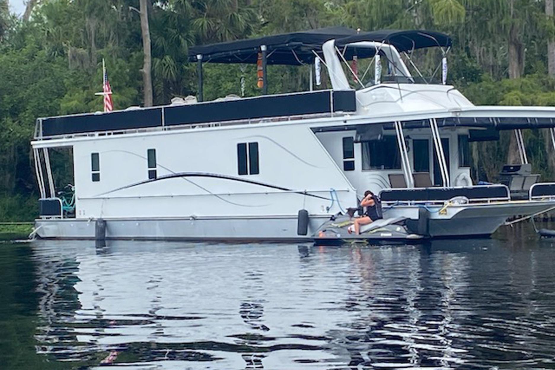 Houseboat Horizon 6015 (2001) on a serene lake with lush greenery in the background.