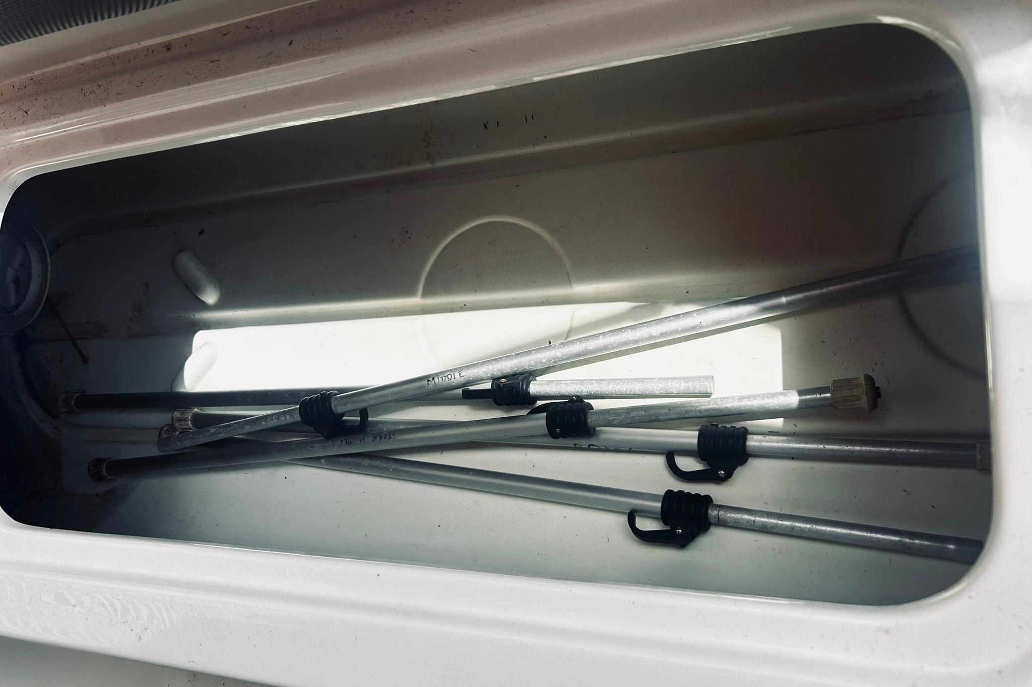 Storage compartment of 2013 Hurricane SunDeck Sport 201 OB with metal rods inside.