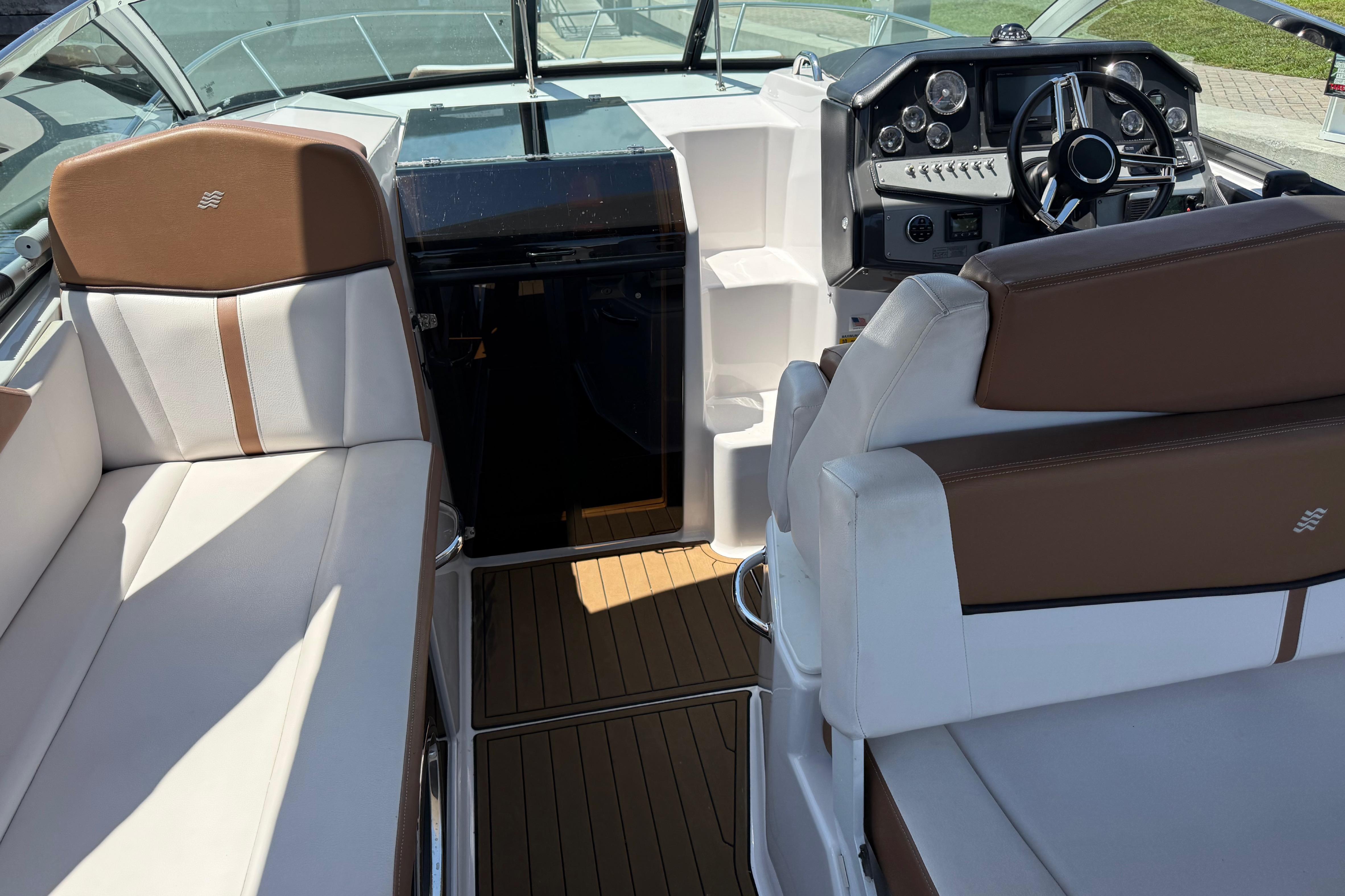 2017 Four Winns V275 boat interior with brown and white seating, modern dashboard, and wood flooring.