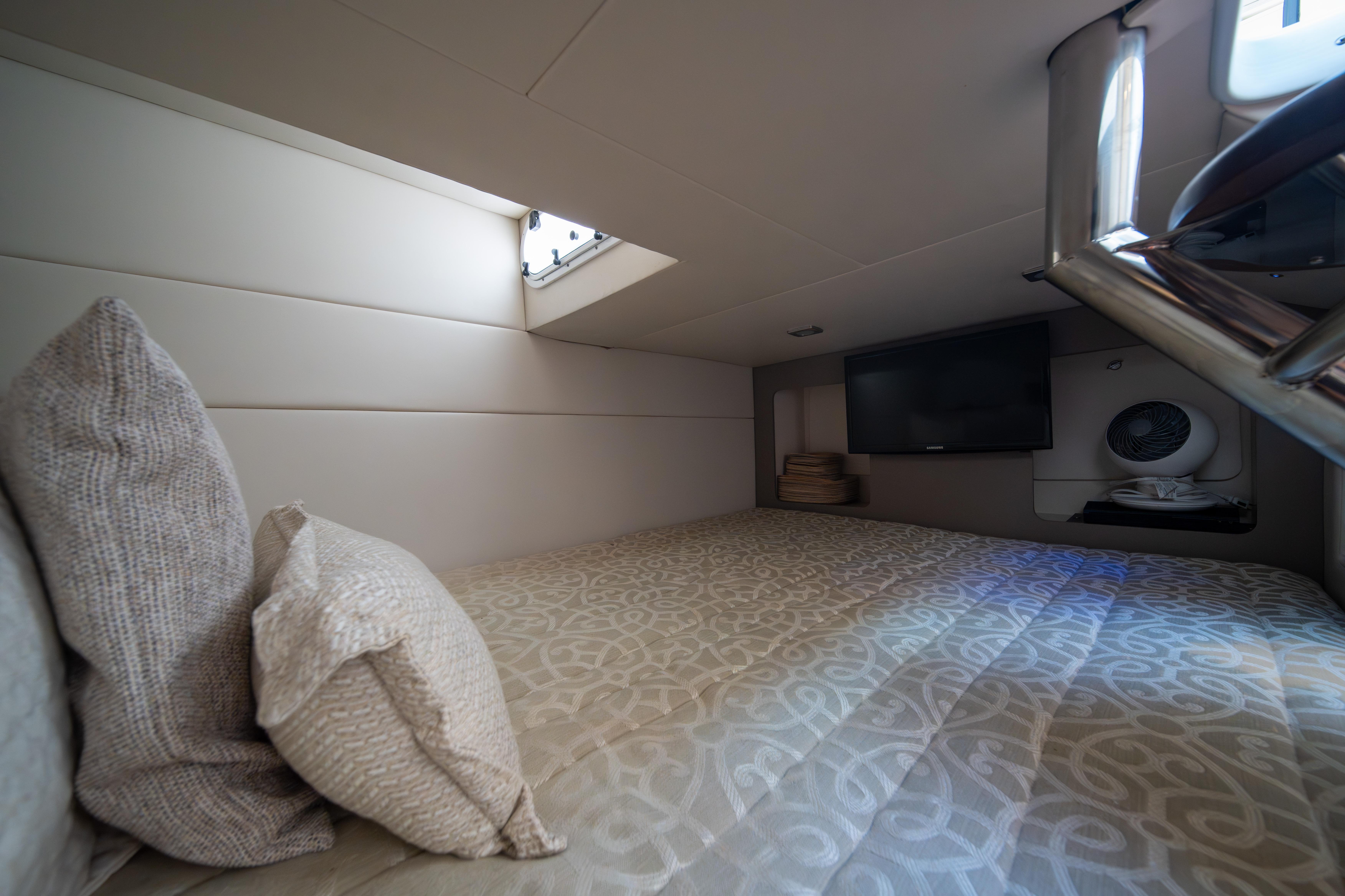 Interior cabin of 2018 Formula 350 Crossover Bowrider OB with cozy bedding and TV.