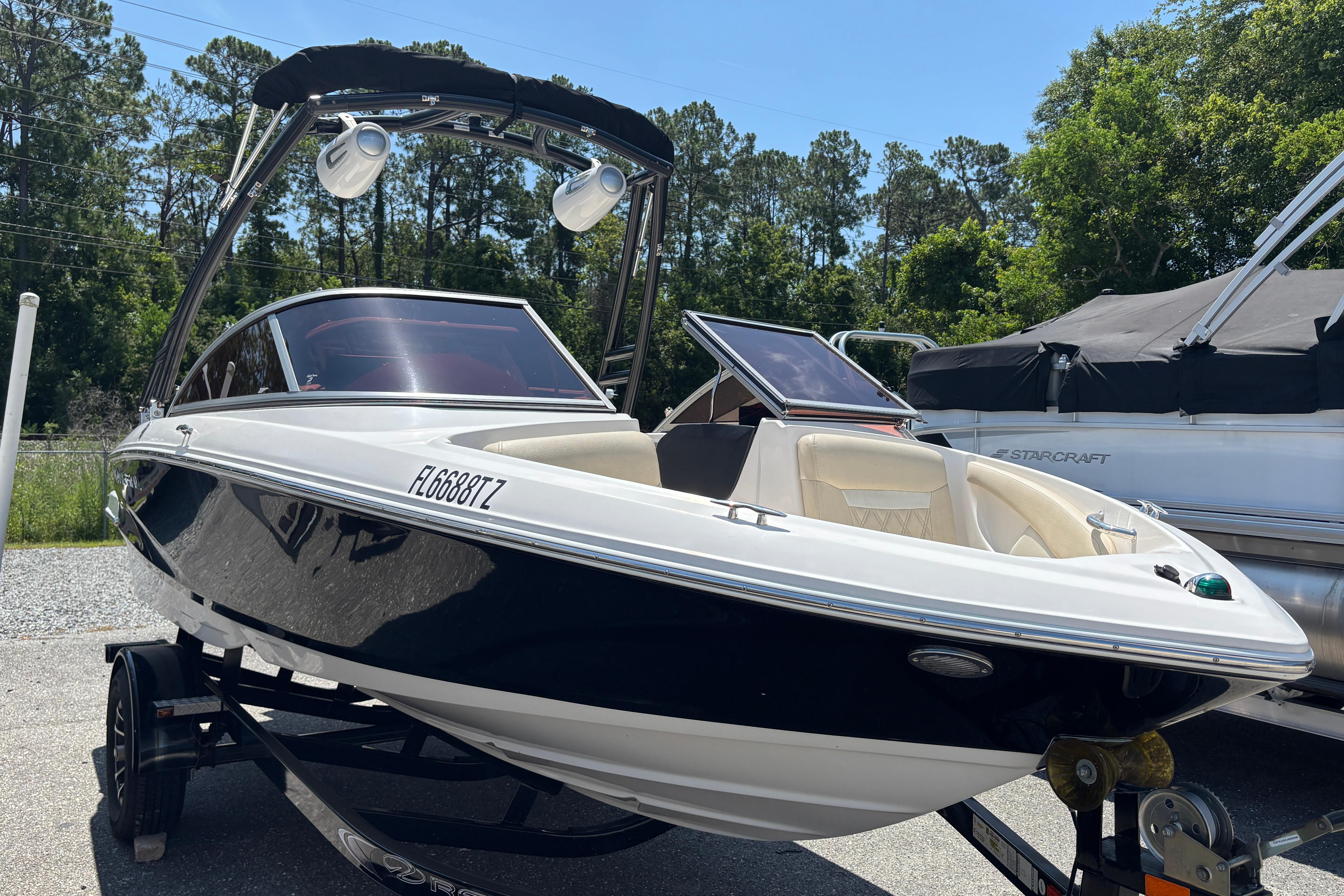 2018 Regal 1900 ES Bowrider boat on trailer, parked outdoors, surrounded by trees.