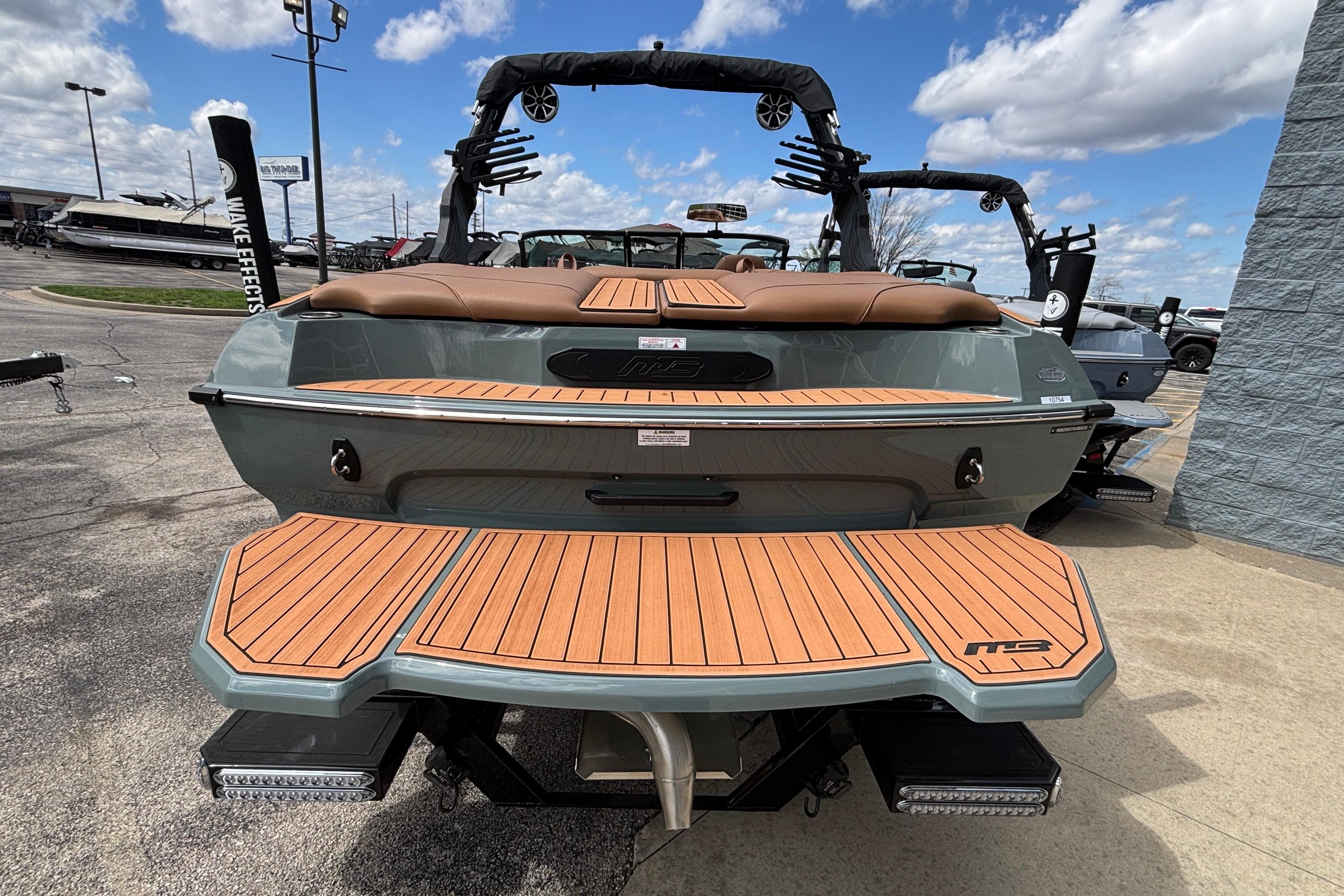 2026 MB B52 23 Classic boat with teak deck, parked outdoors under blue sky.