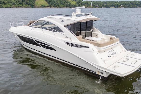 2016 Sea Ray Sundancer 510 yacht cruising on a serene lake with lush green shoreline.