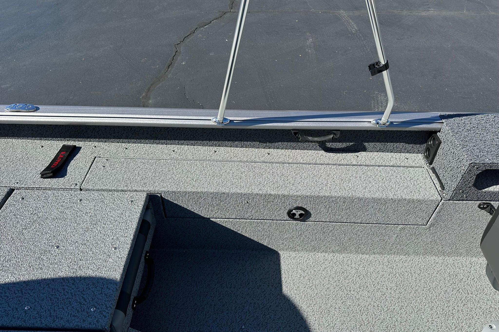 2026 Lund 1875 Impact XS Sport boat interior with gray carpet and storage compartments.