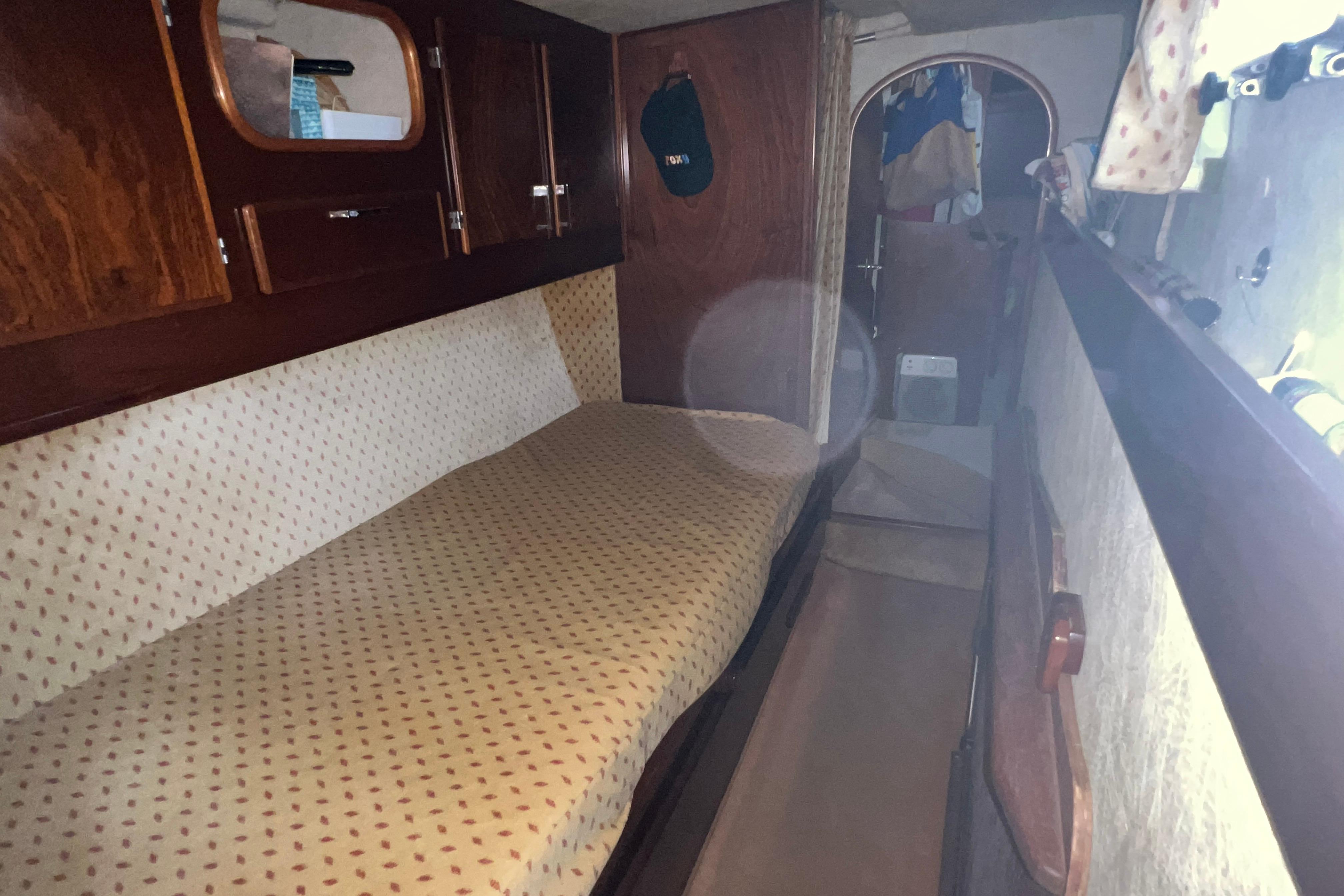 1998 Amel Super Maramu cabin interior with wooden finishes and patterned bedding.