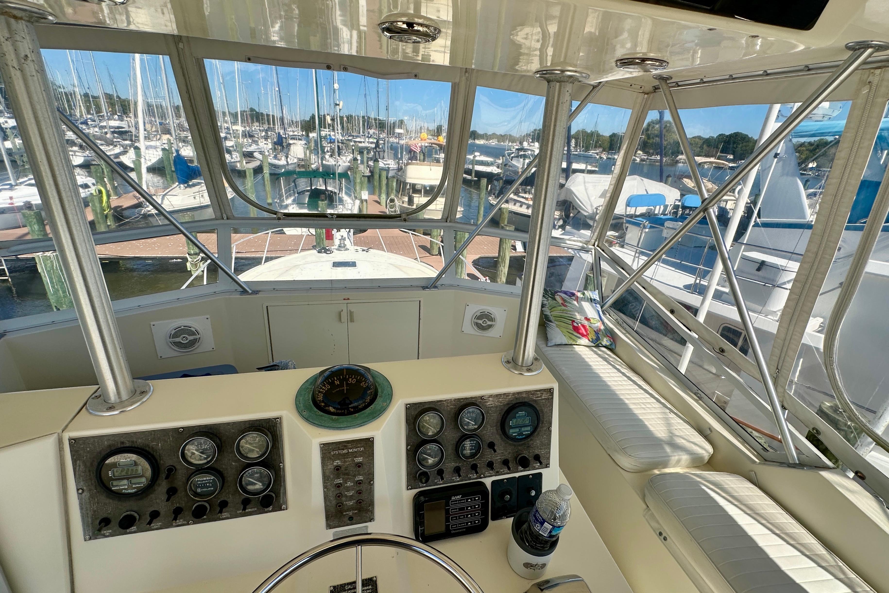 Helm of 1989 Viking 48 yacht with marina view, featuring gauges and seating.