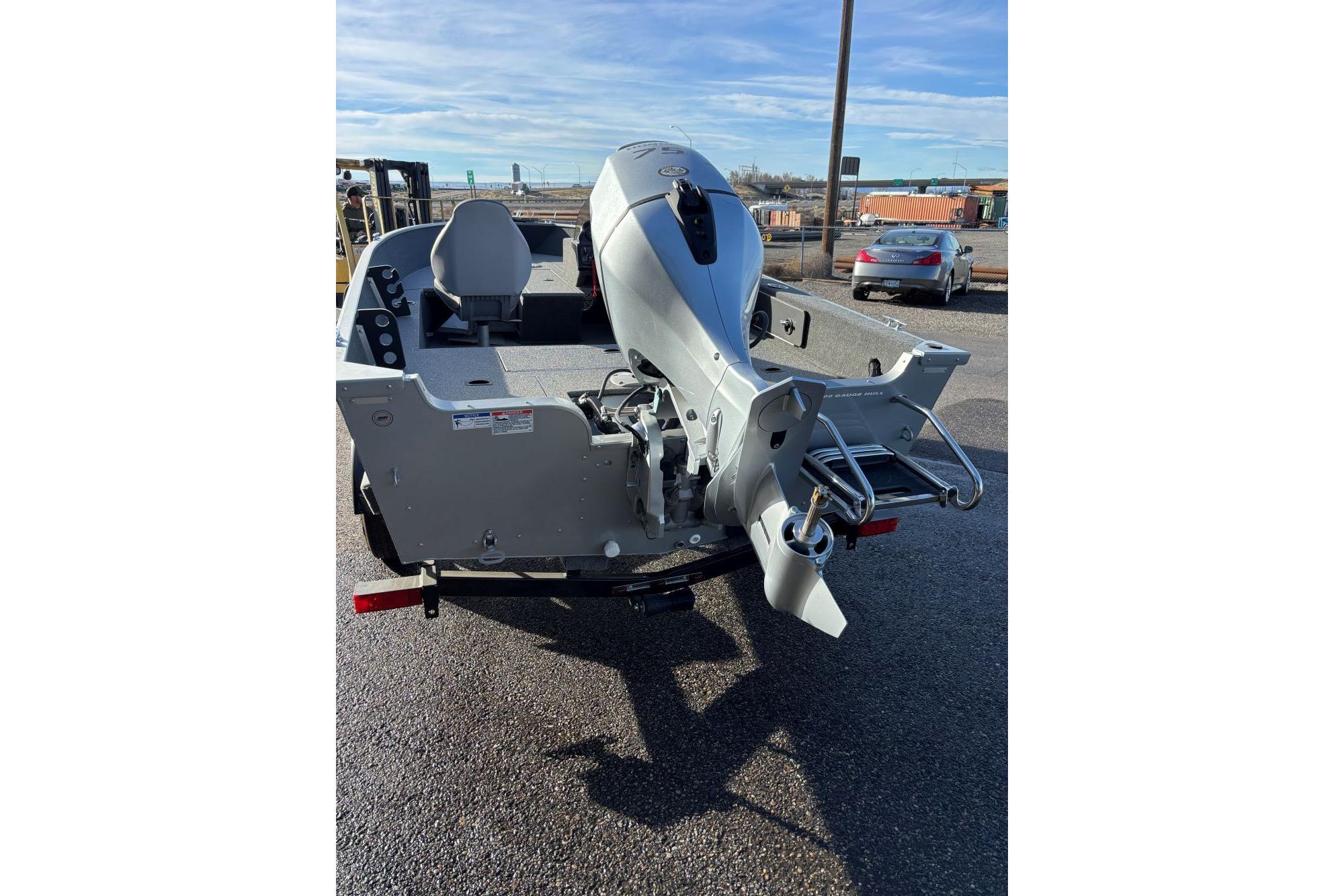 2024 Starweld 16 Fusion SC Pro boat with outboard motor, parked on asphalt.