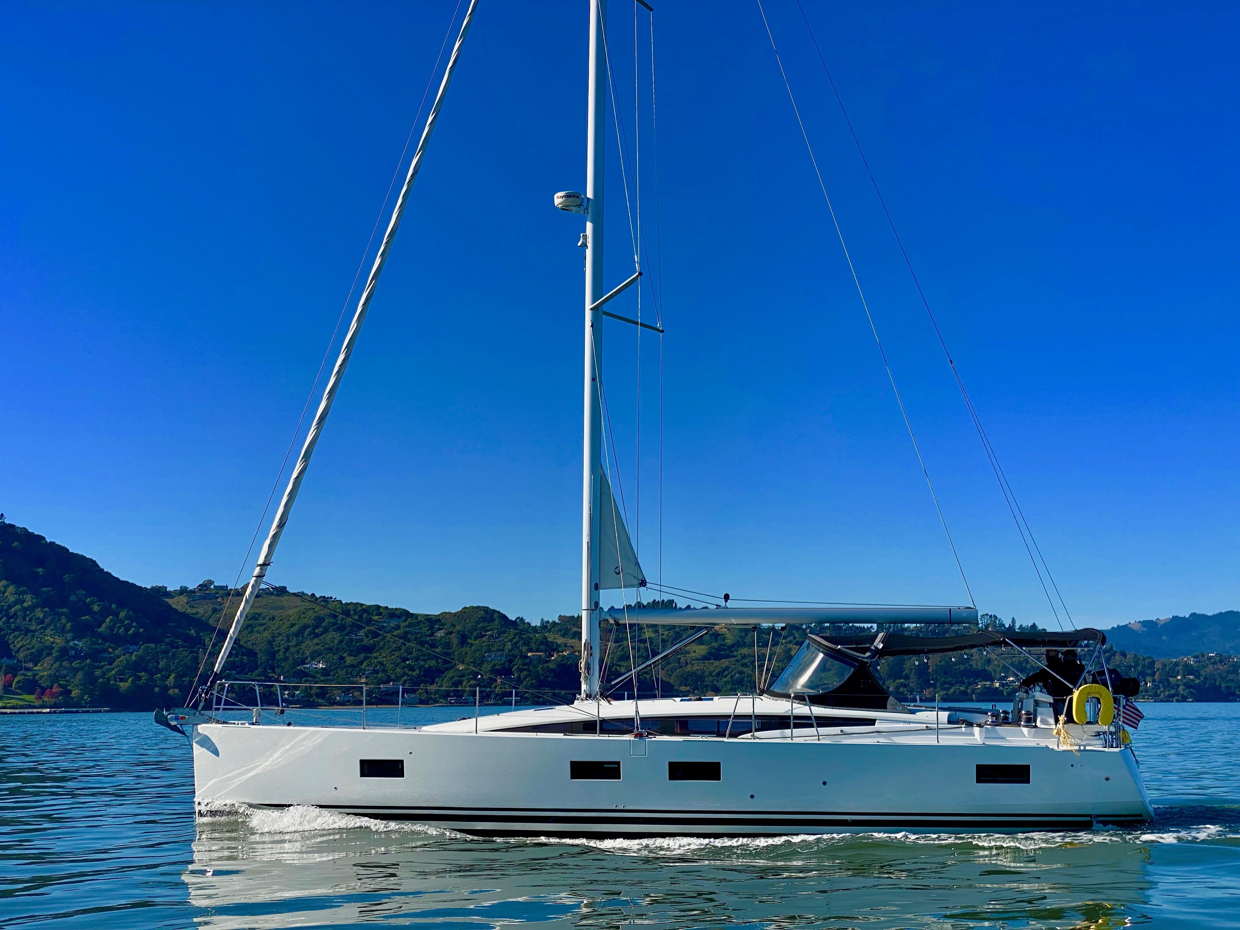 2016 Jeanneau 54 sailboat cruising on calm waters under a clear blue sky.