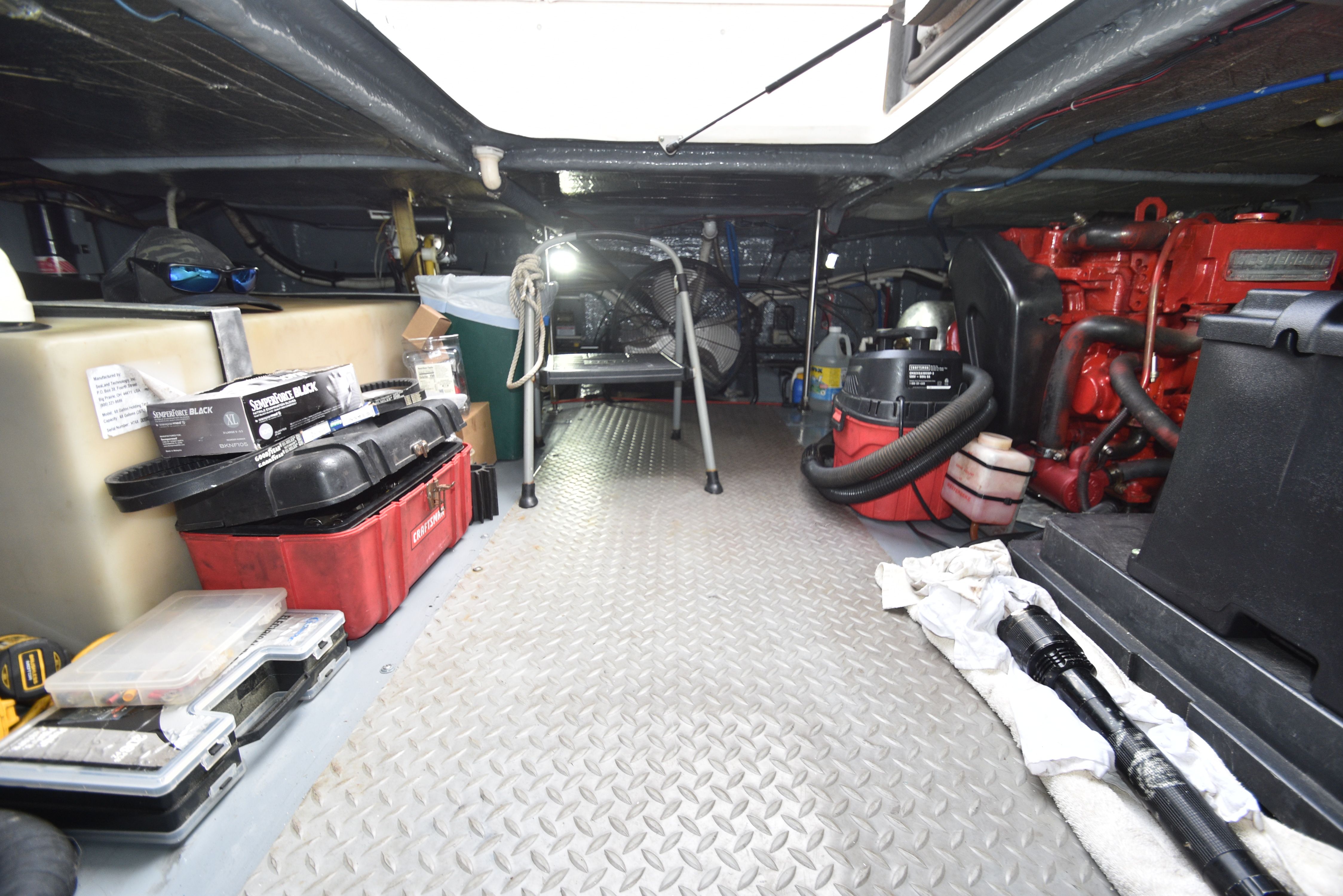 The engine room of a 2000 Sea Ray 480 Sedan Bridge with tools and equipment.