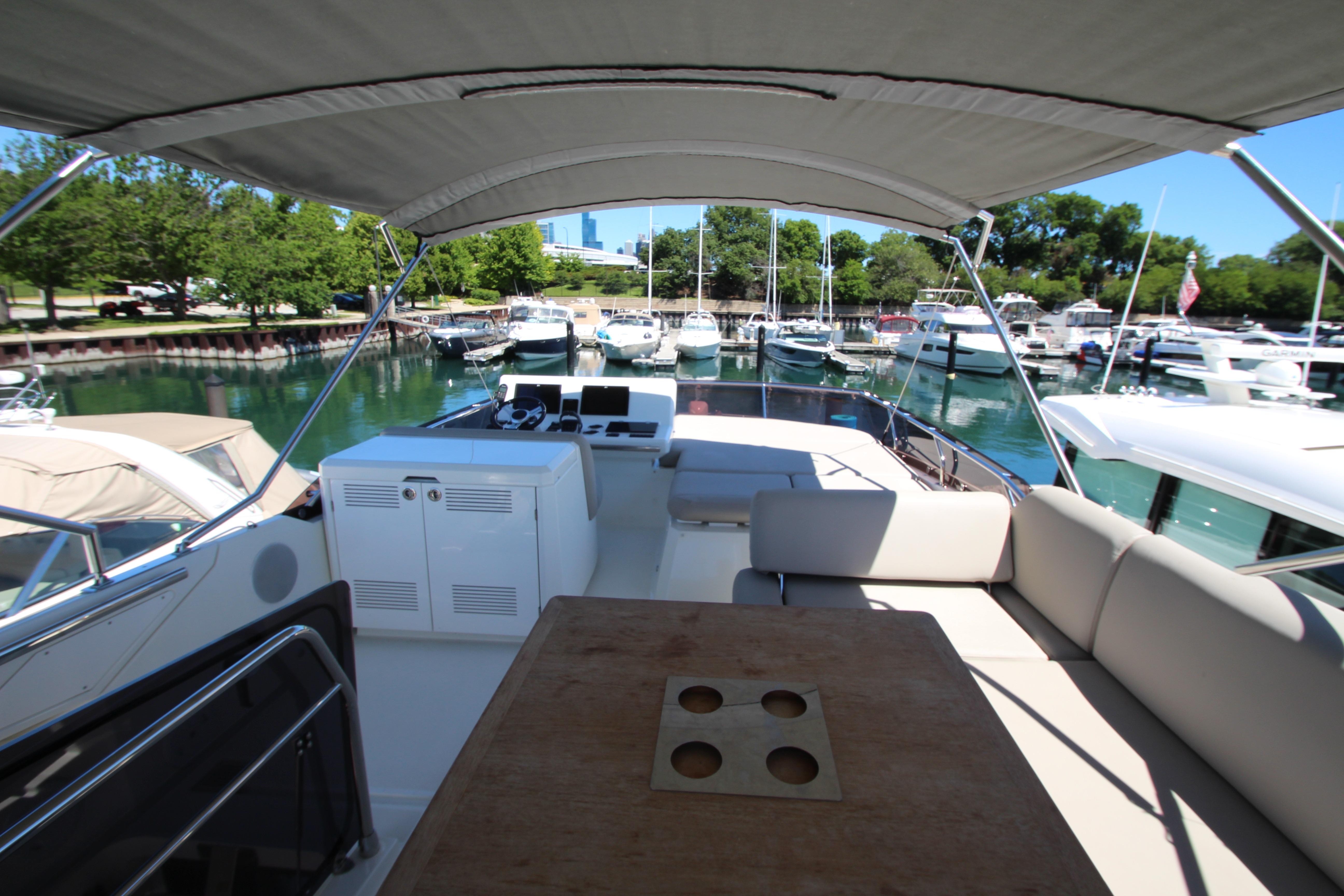 Prestige 520 yacht interior, 2022 model, docked in a marina with lush greenery.