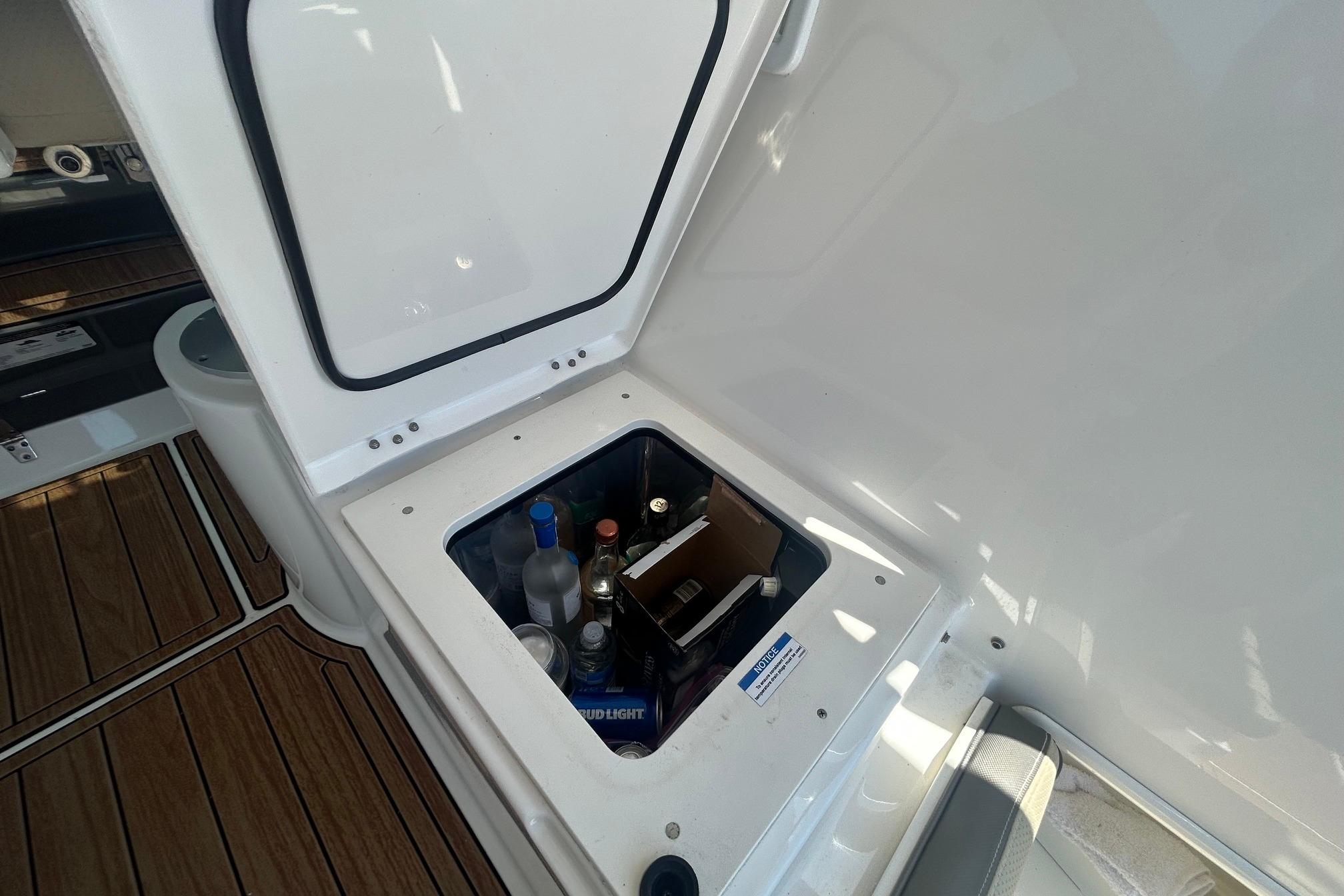 Storage compartment on 2019 Pursuit OS 355 Offshore boat, containing various bottles and beverages.