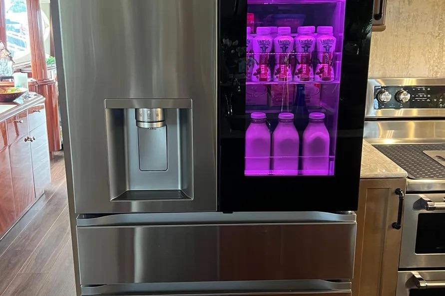 Modern stainless steel refrigerator with purple-lit beverage display on a 2004 Lazzara SC Motor Yacht.