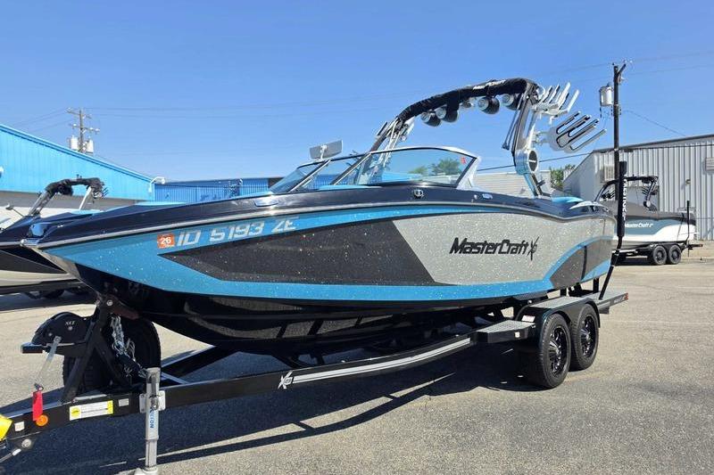 2017 MasterCraft X23 boat on trailer, blue and gray, parked outdoors.