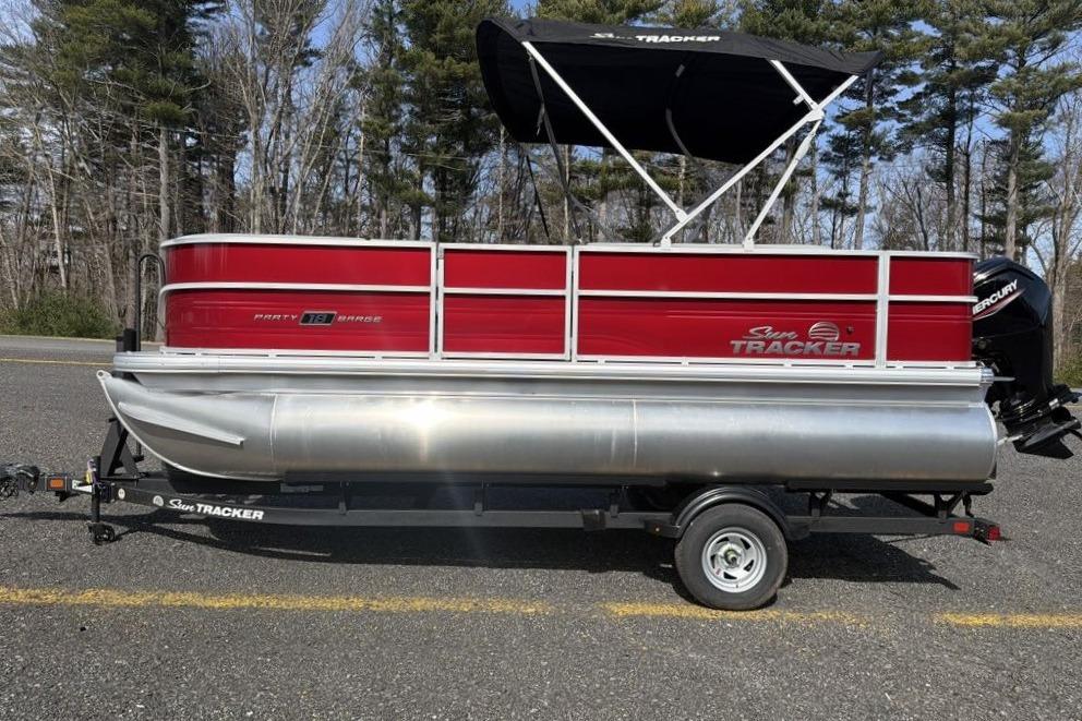 2026 Sun Tracker Party Barge 18 DLX pontoon boat with red exterior and canopy.