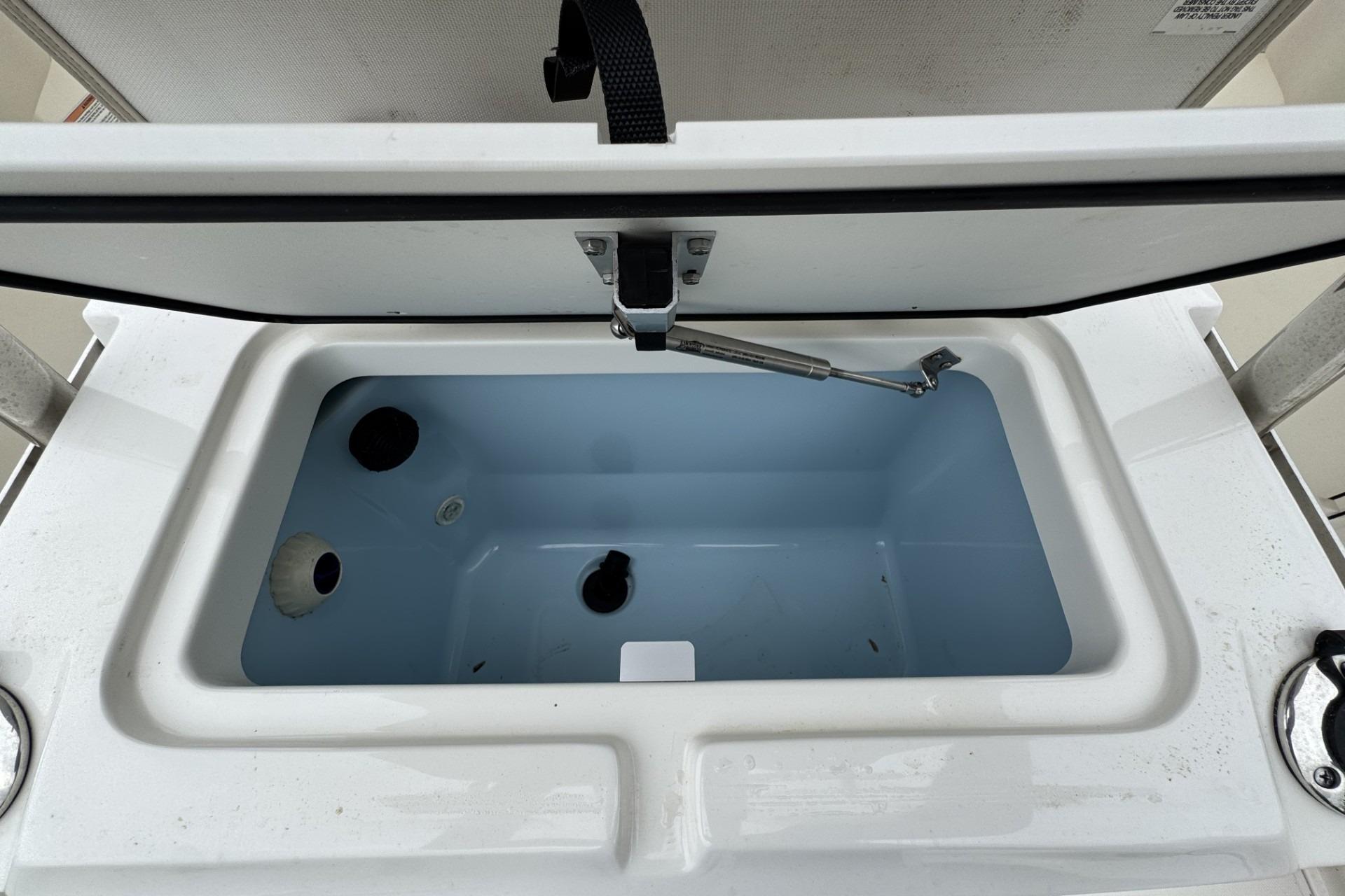 Open storage compartment on 2024 Boston Whaler 230 Outrage boat, showcasing interior design.
