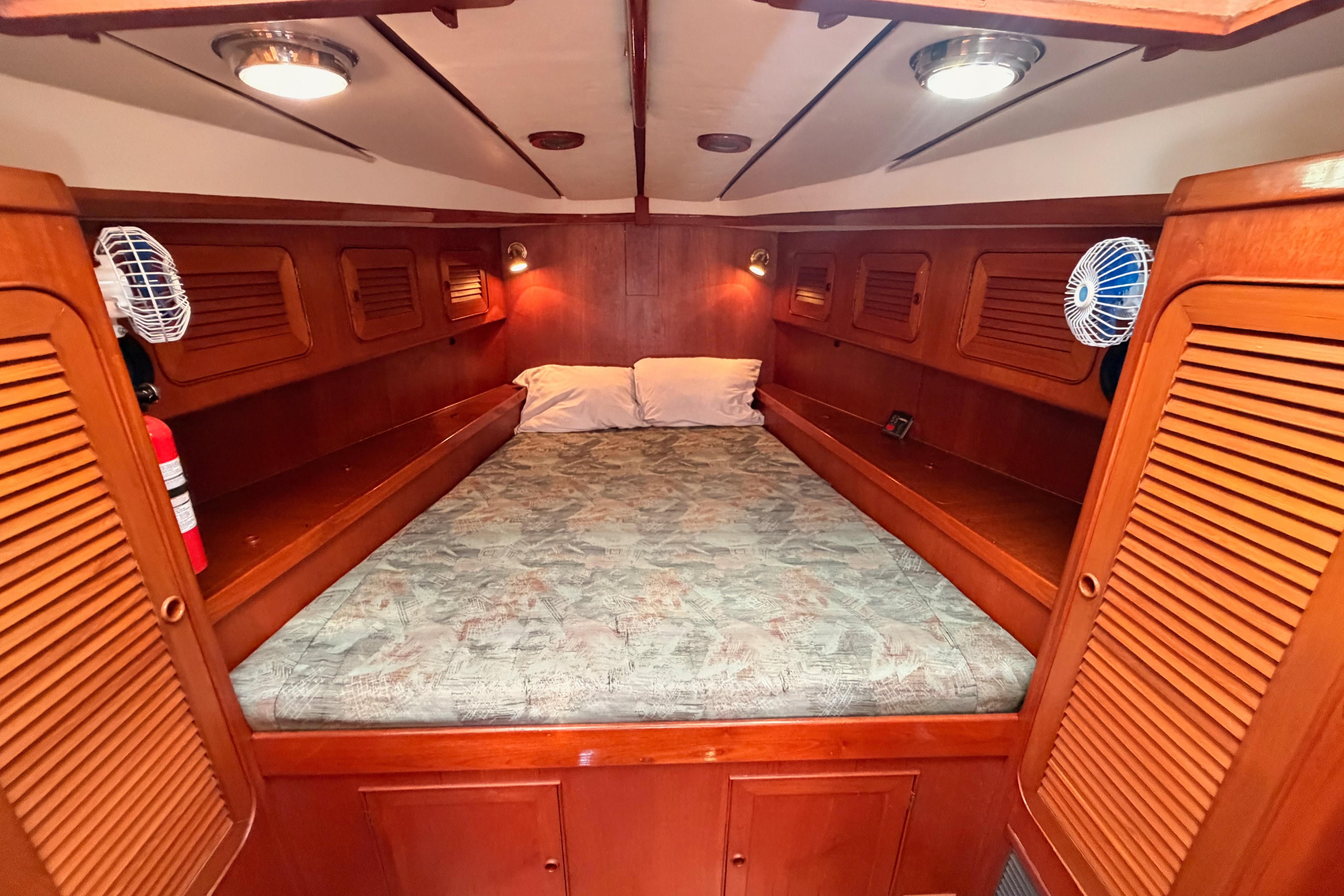 Cozy cabin interior of a 1991 Hylas 51 yacht with wood paneling and bedding.