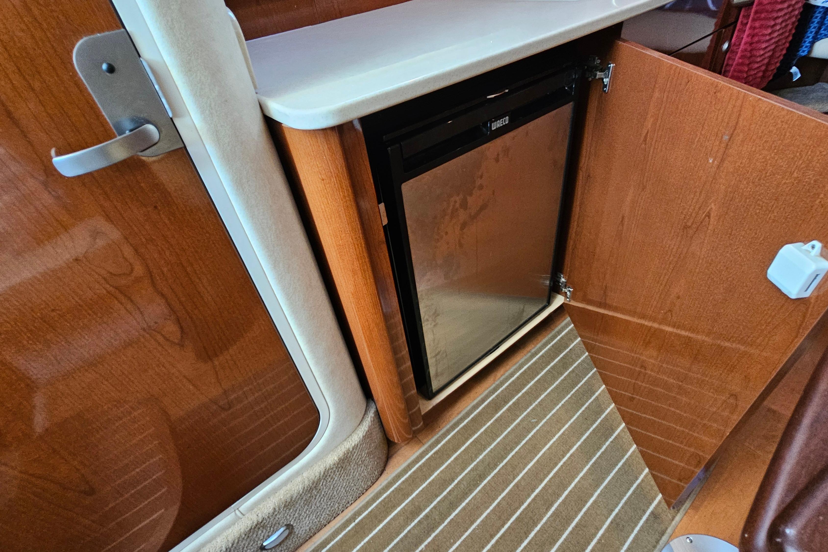 2008 Sea Ray Sundancer 350 interior with open cabinet revealing a compact fridge.