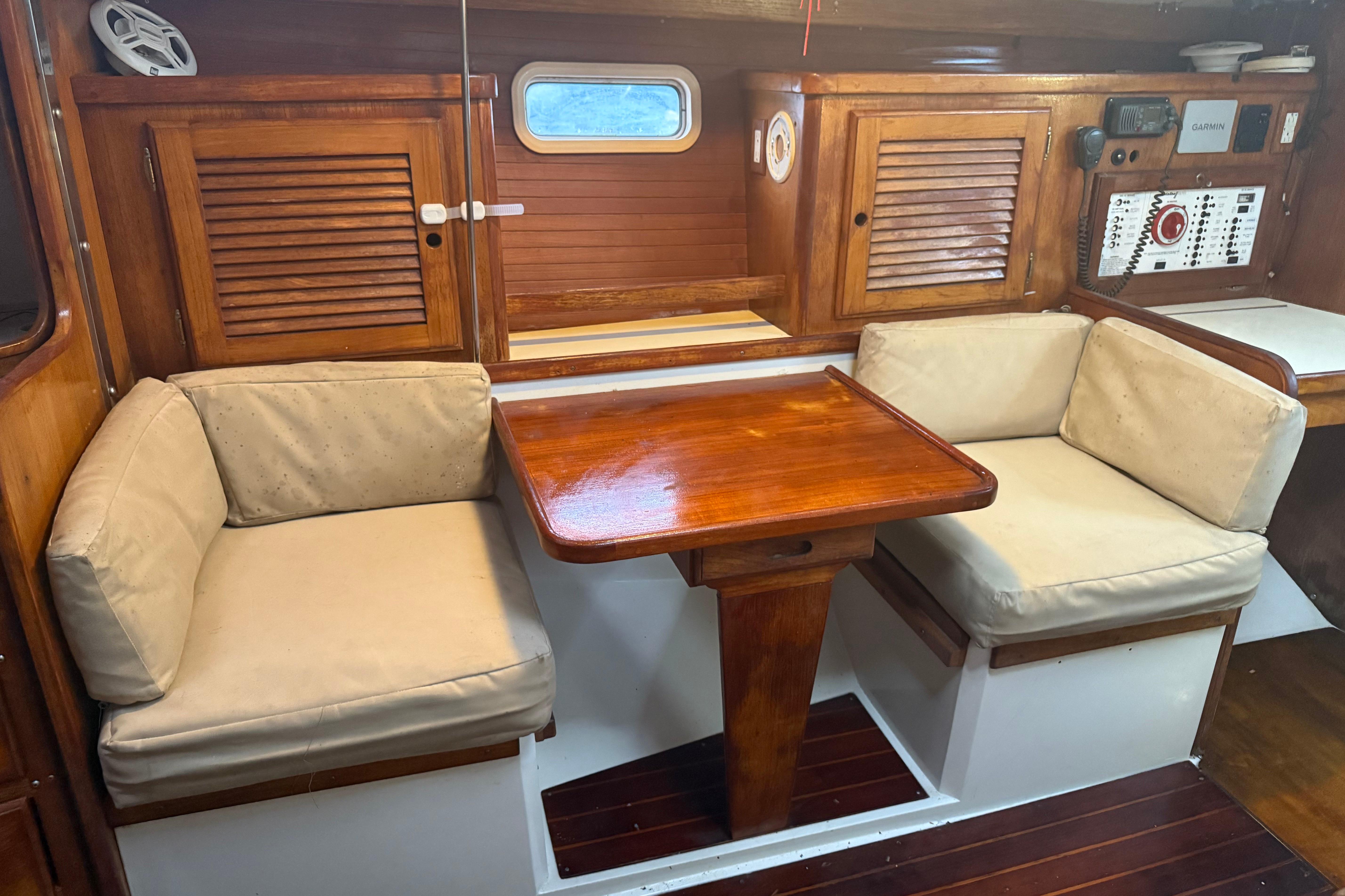 Cozy interior of 1995 Catalina 36 MkII sailboat with wooden table and cushioned seating.