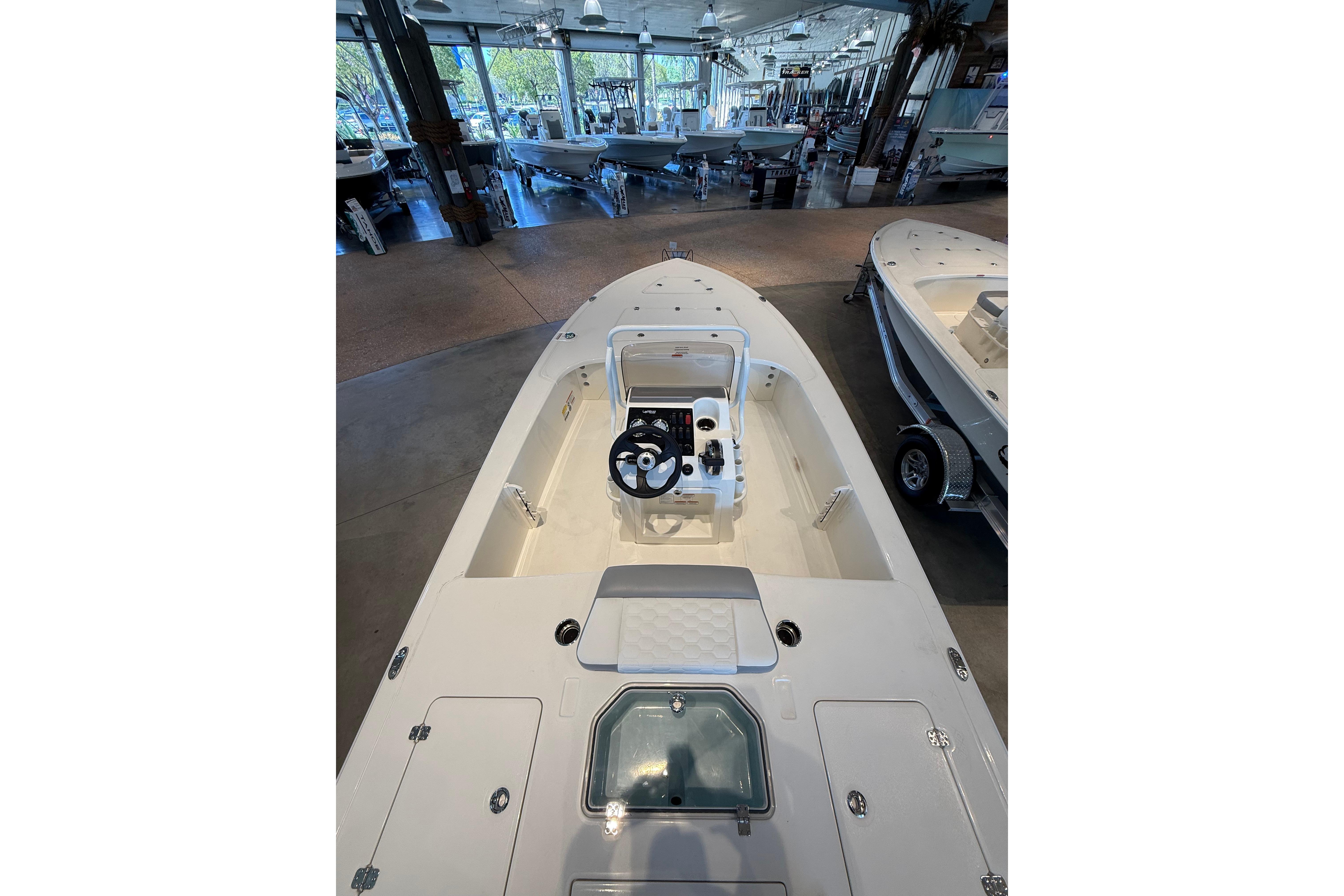 2026 Mako 18 Pro Skiff boat interior in showroom, featuring steering console and seating.