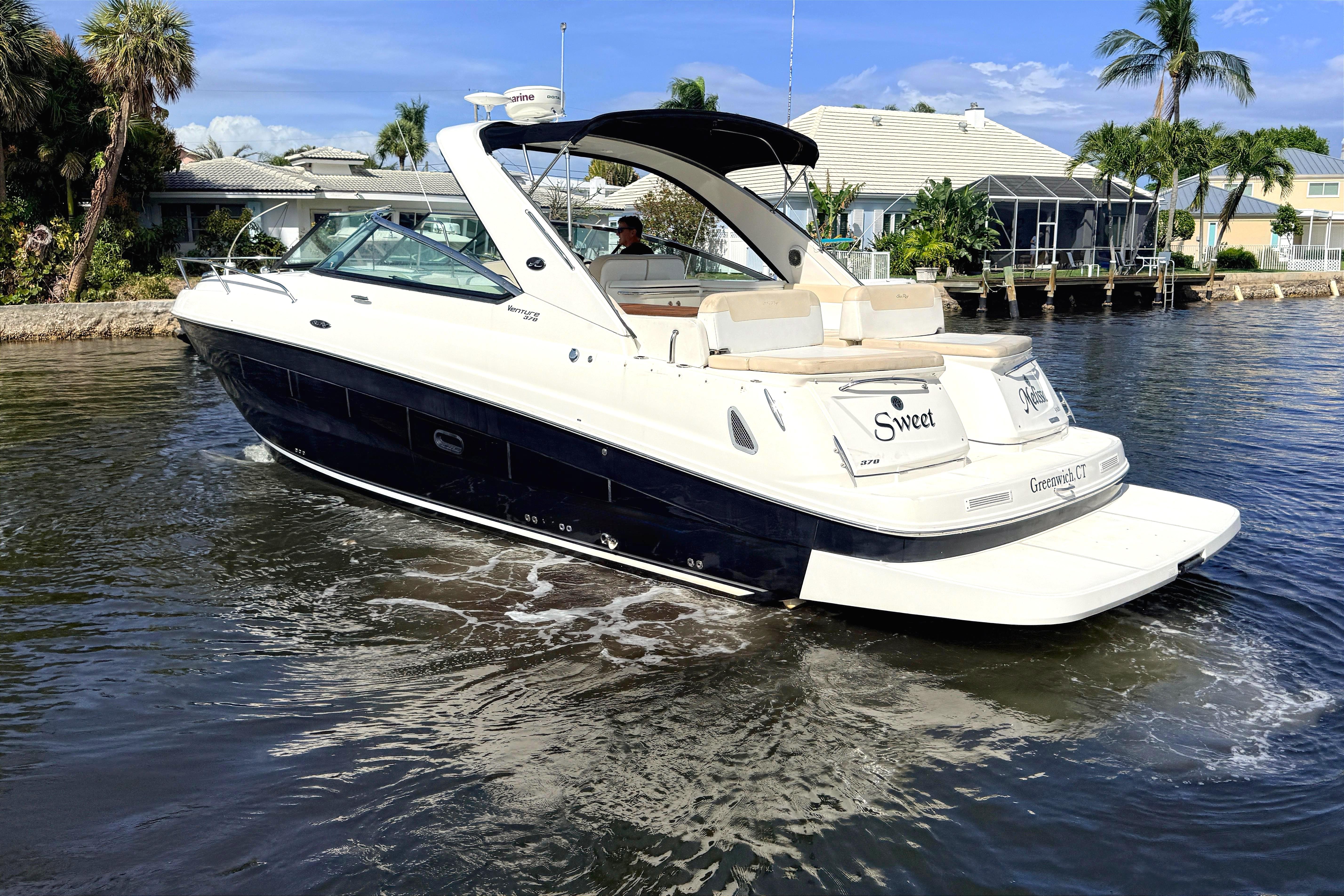 2013 Sea Ray 370 Venture boat cruising on a sunny day near waterfront homes.