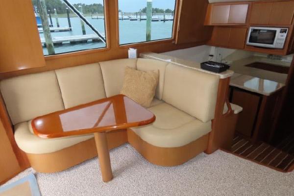 Henriques 42 Flybridge 2011 interior with beige seating, wooden table, and kitchenette.