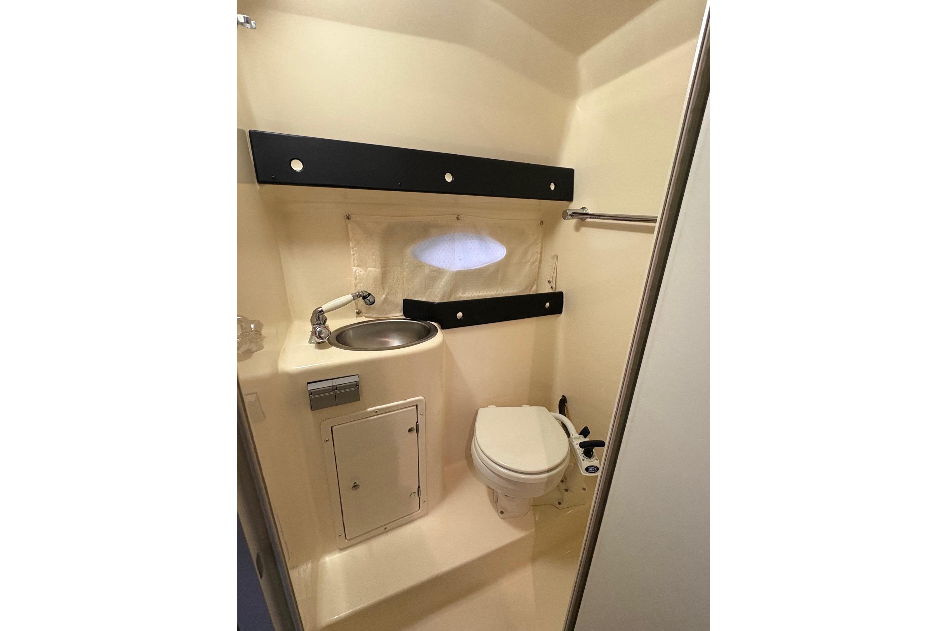 2003 Rinker Fiesta Vee 270 boat bathroom with sink, toilet, and storage cabinet.
