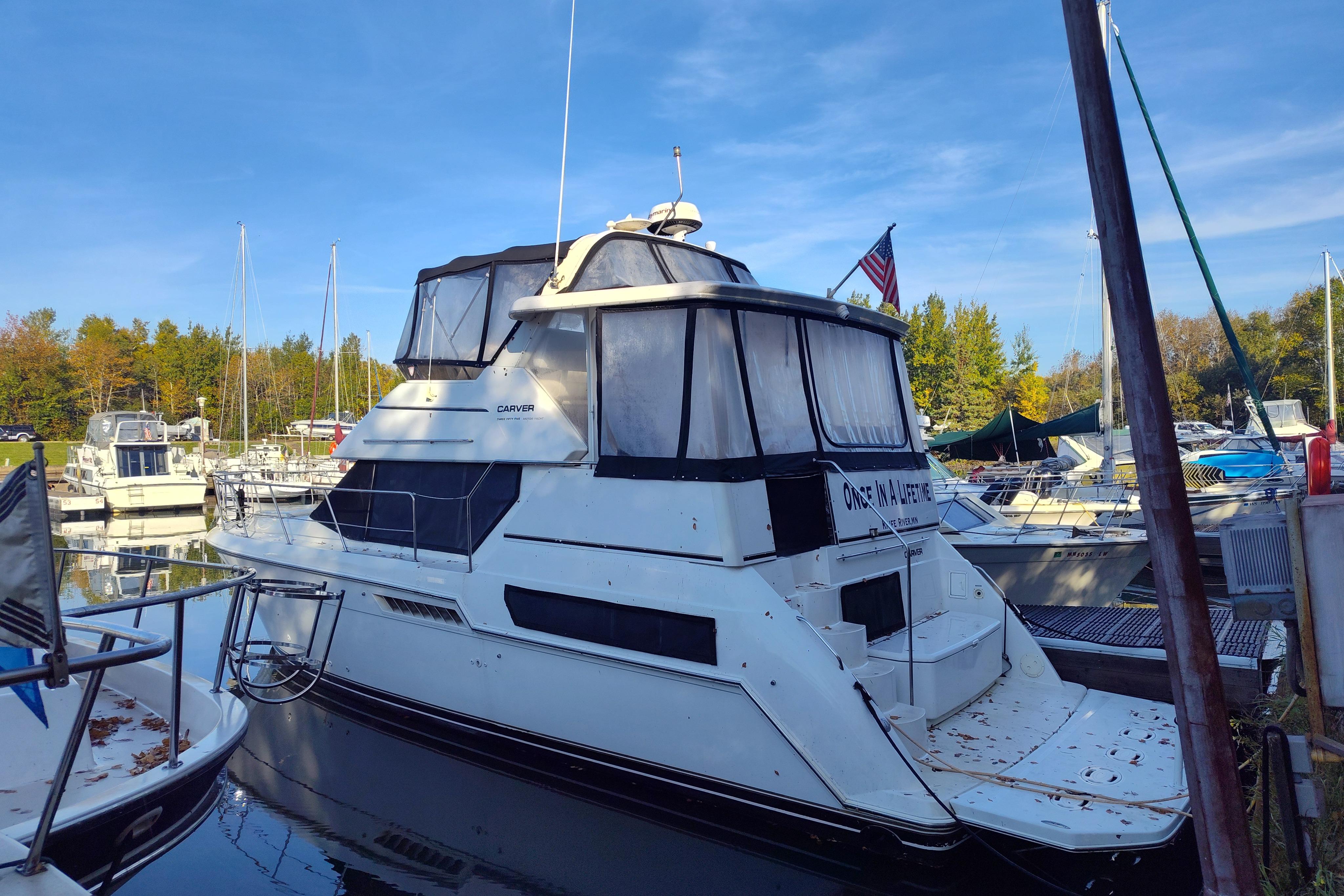 1998 Carver 355 Aft Cabin Motor Yacht docked in a marina, surrounded by other boats.