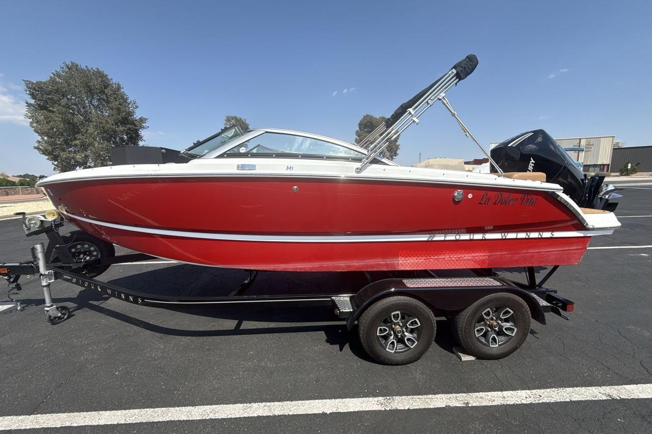 2024 Four Winns H1 OB boat in red on a trailer, parked outdoors.