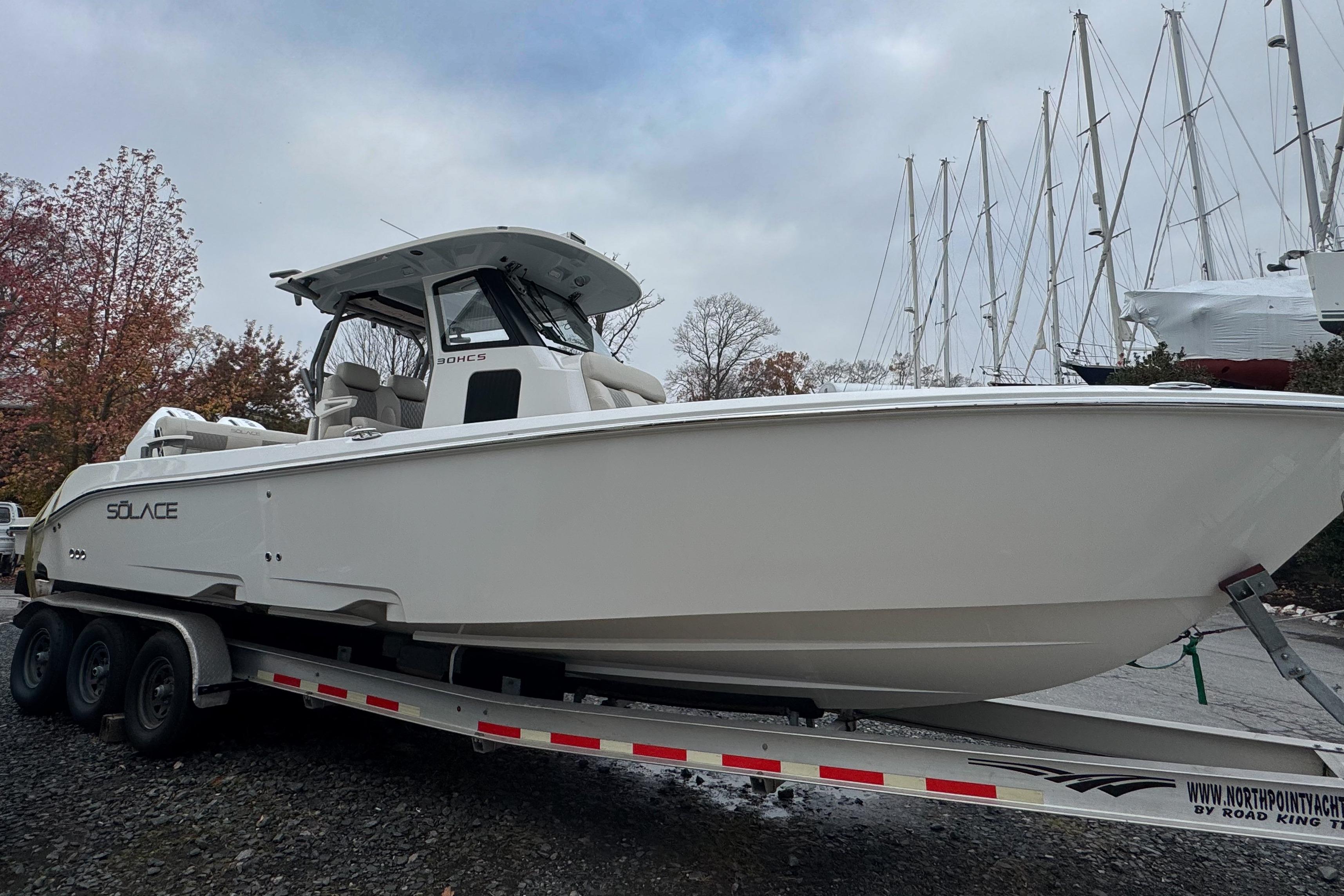 2025 Solace 30 HCS boat on trailer, surrounded by trees and sailboats.