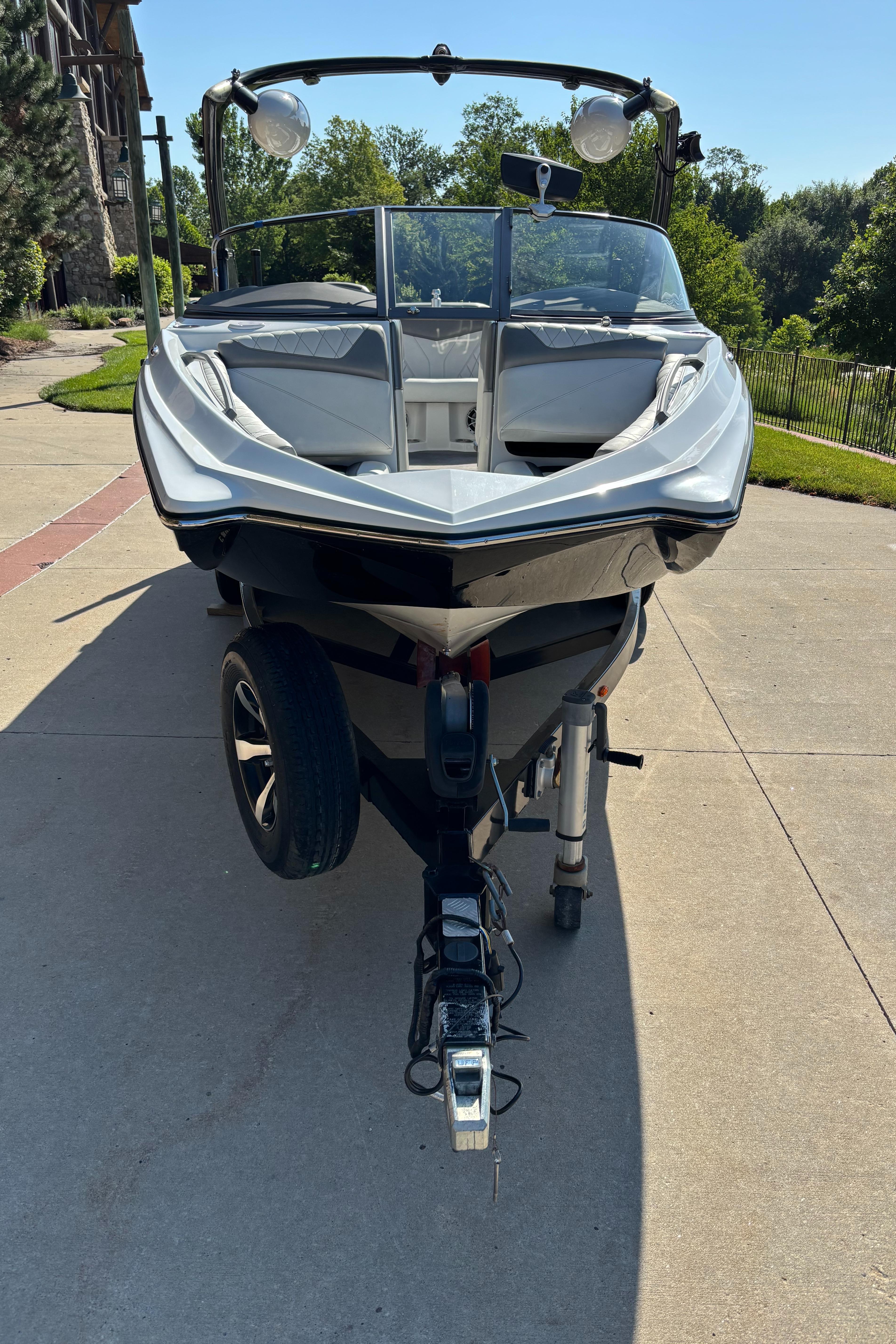 2014 Tigé RZR boat on trailer, parked on driveway, surrounded by greenery.