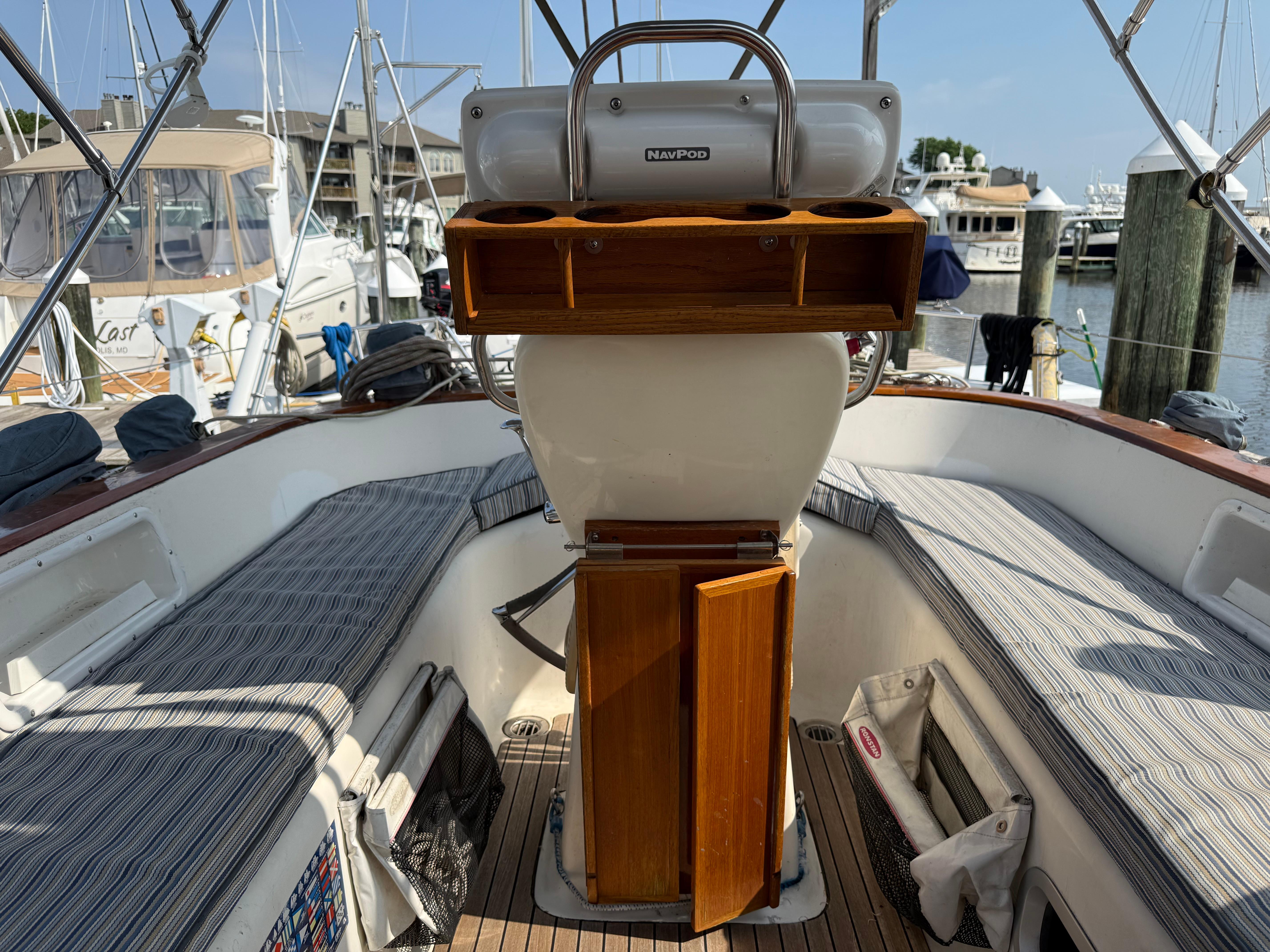 Cockpit of 1999 Bavaria 42 Ocean sailboat with striped seating and wooden helm station.
