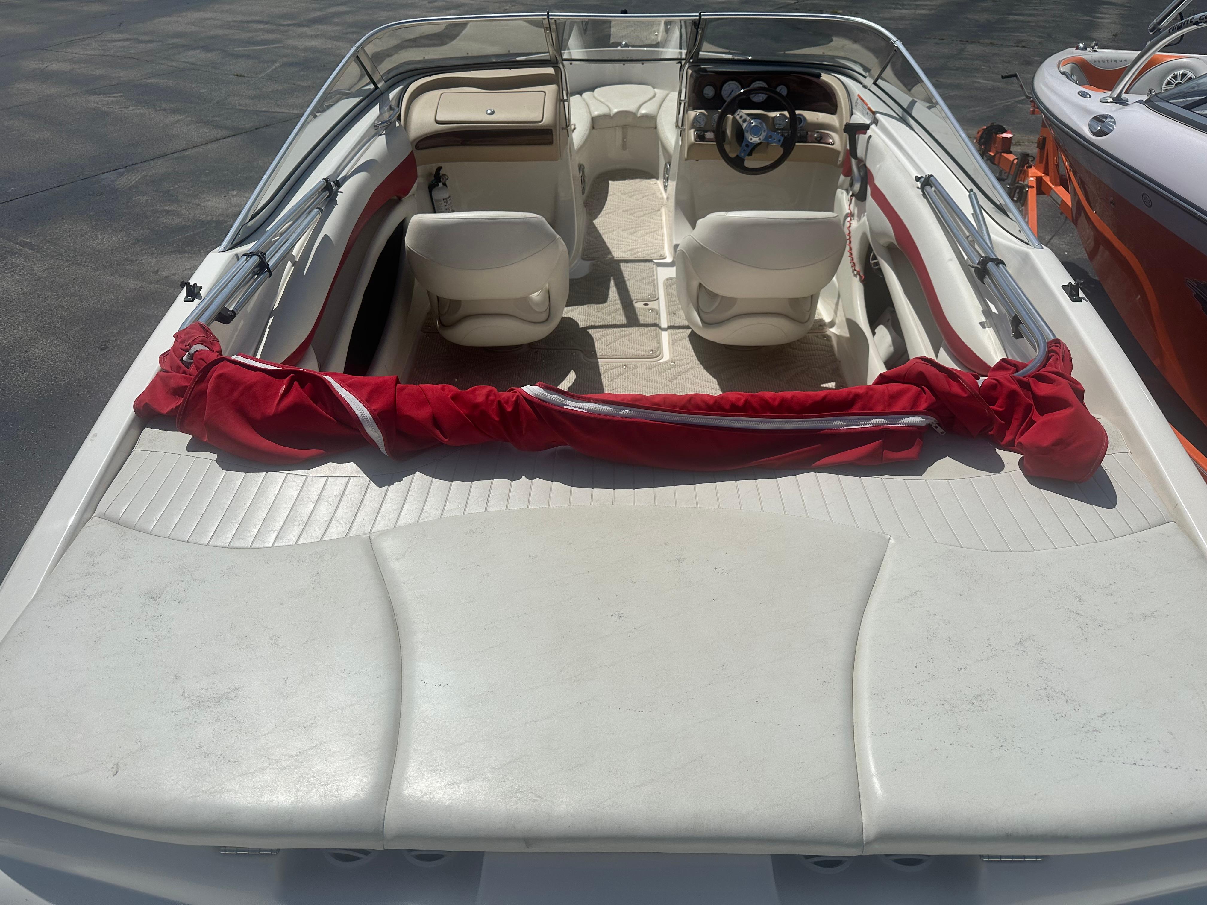 2008 Glastron 205 GX boat interior with white seating and red cover, parked on pavement.