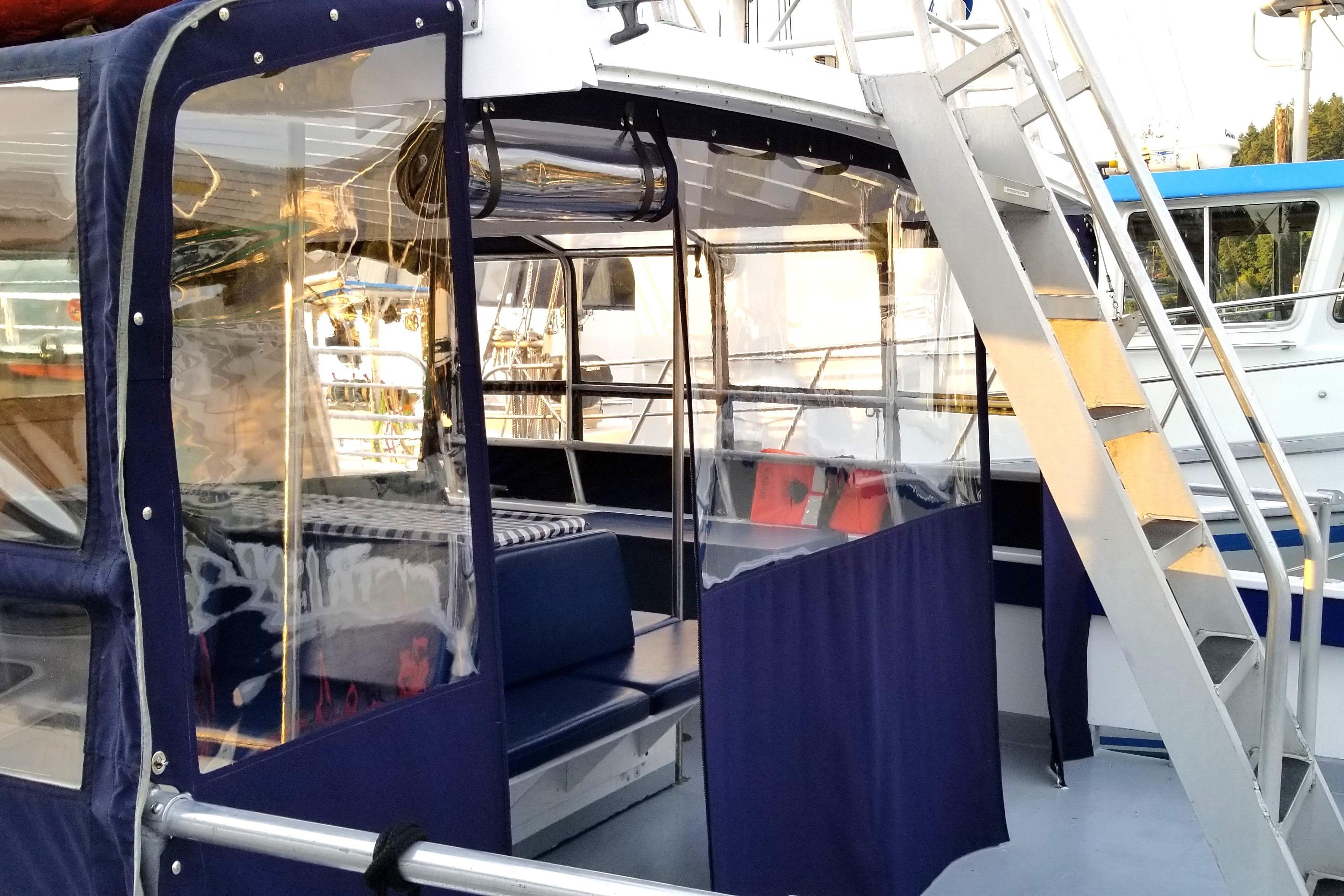 1964 Grandy Tour Boat with blue seating and clear enclosures, docked with visible stairs.