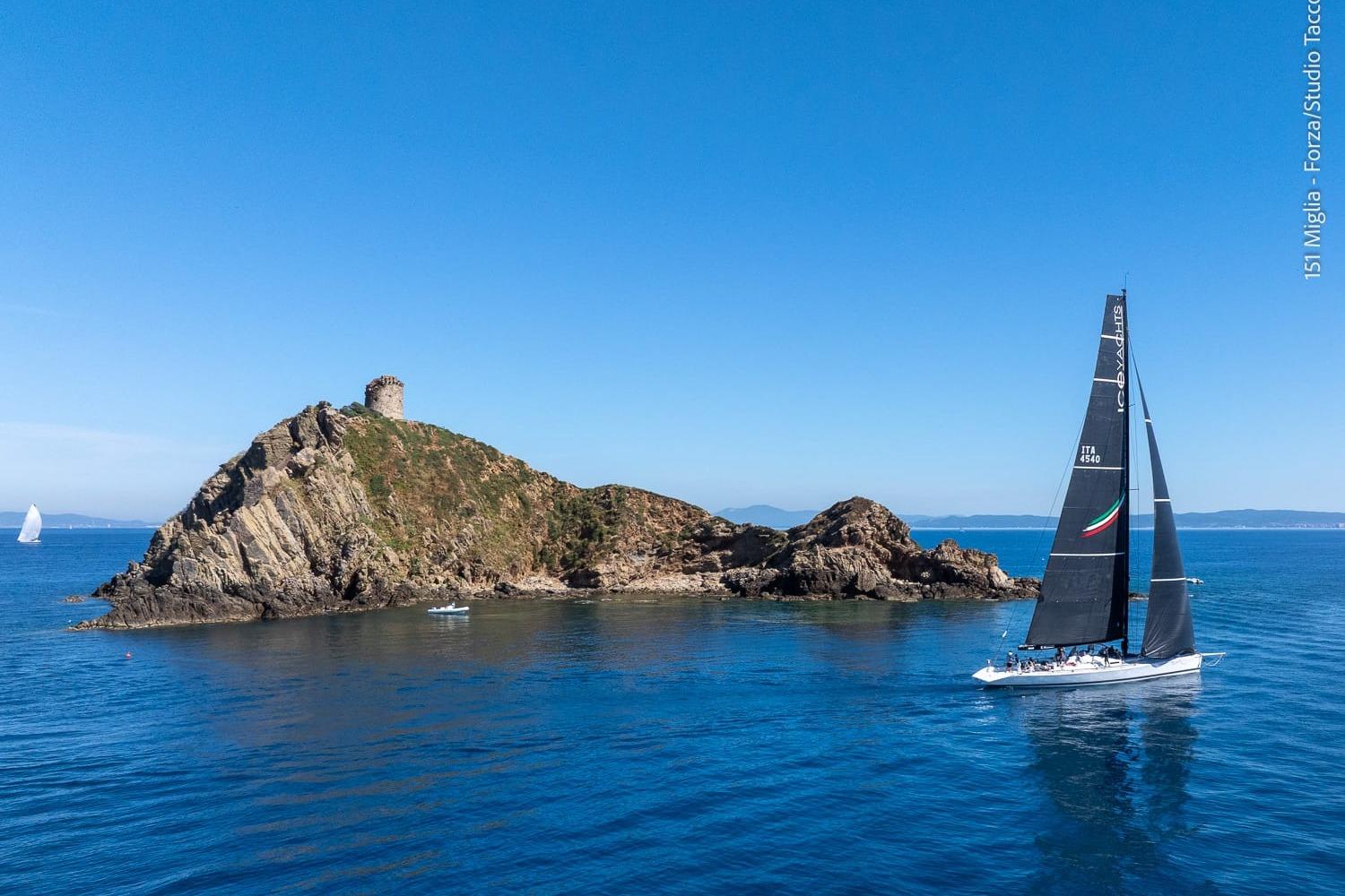 Sailboat McConaghy Reichel Pug 79, 1995, near rocky island with tower, clear blue sky.