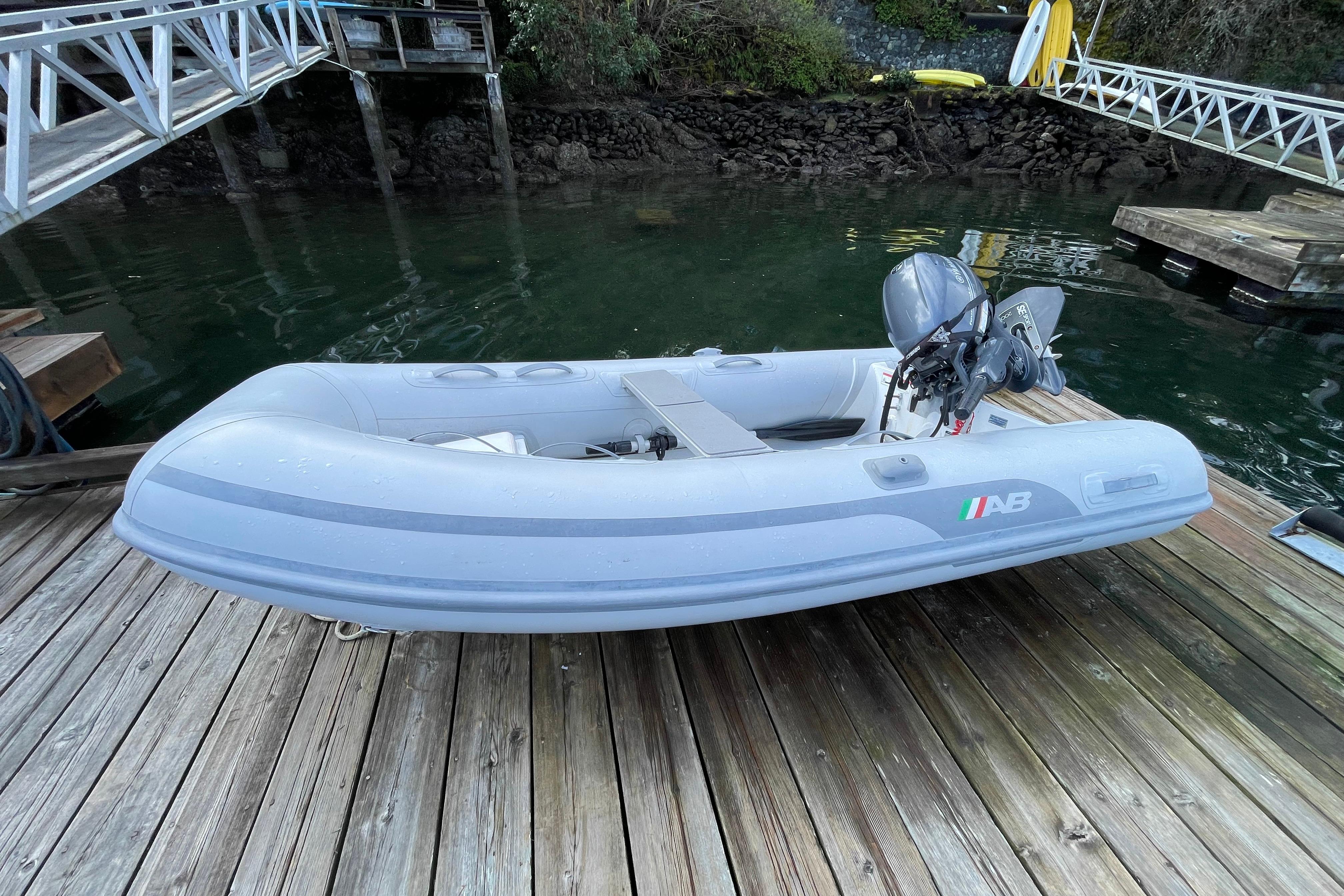 Inflatable boat with motor docked on wooden pier, near water.
