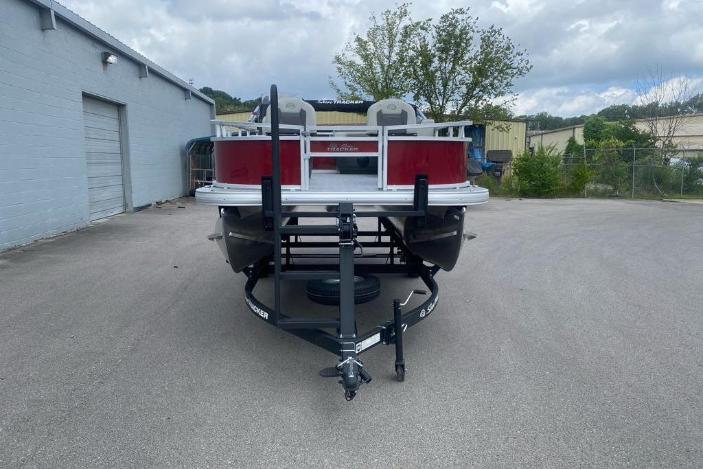 2026 Sun Tracker Bass Buggy 16 XL Select pontoon boat on trailer, parked outdoors.